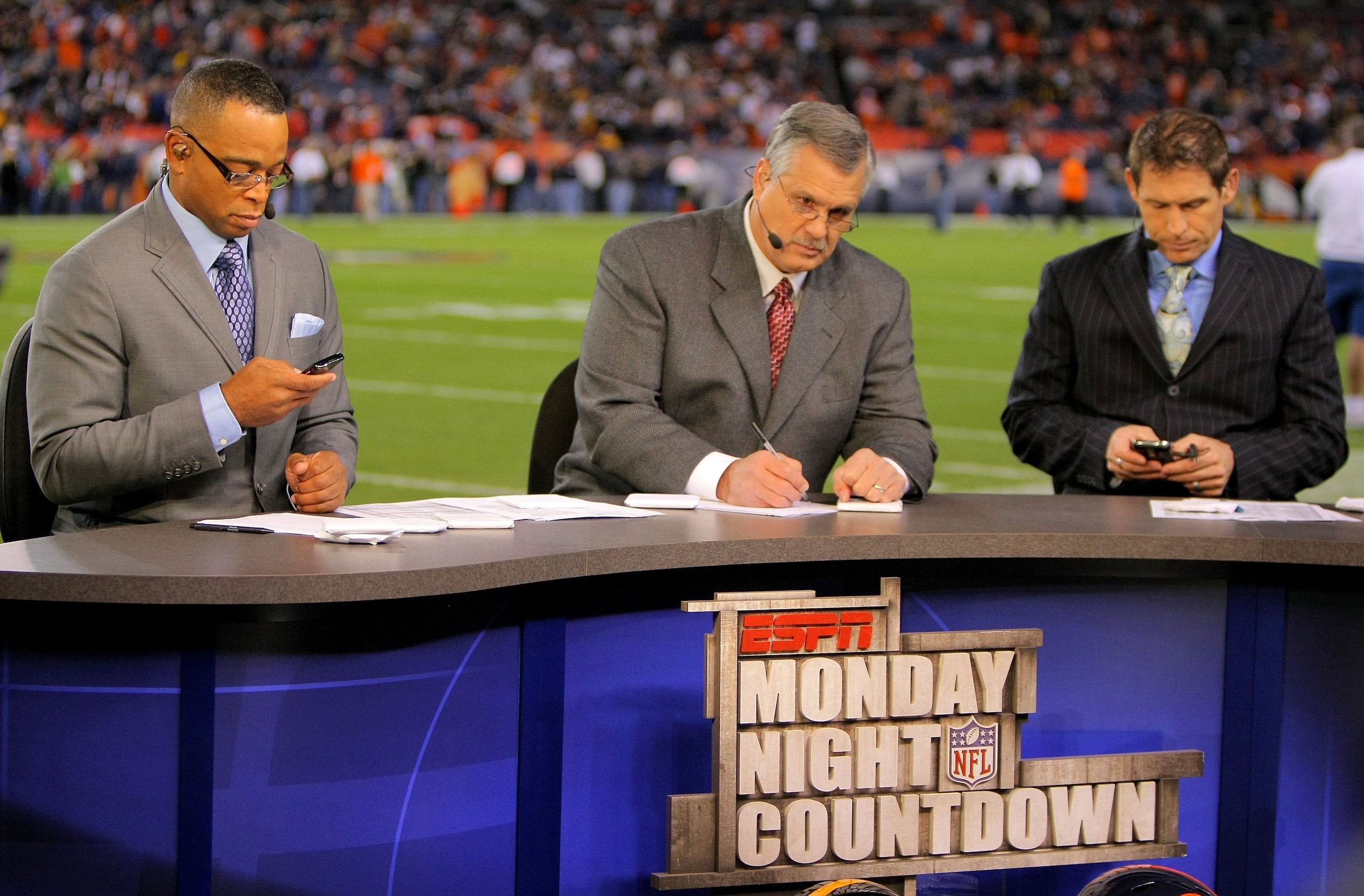DENVER - NOVEMBER 09:  Matt Millen (C) works on the set of the pregame show for ESPN's Monday Night Football as his co hosts Stuart Scott (L) and Steve Young (R) work on their personal electronic devices as the Pittsburgh Steelers face the Denver Broncos 