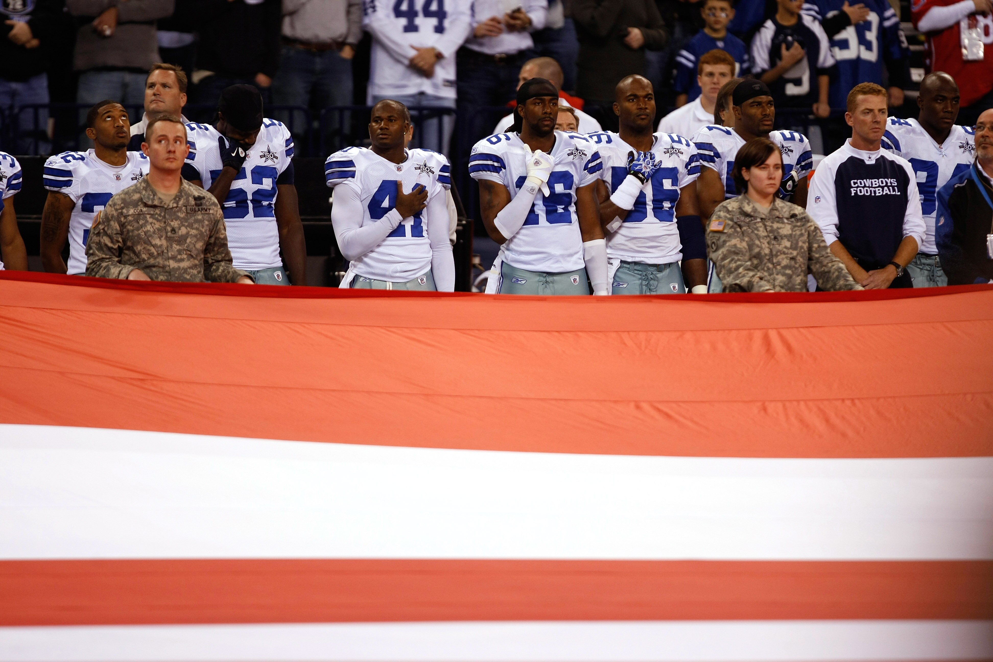 INDIANAPOLIS, IN - DECEMBER 05: Dallas Cowboys players stand during the National Anthem as members of the miltary hold a large flag prior to the game between the Indianapolis Colts against the Dallas Cowboys at Lucas Oil Stadium on December 5, 2010 in Ind