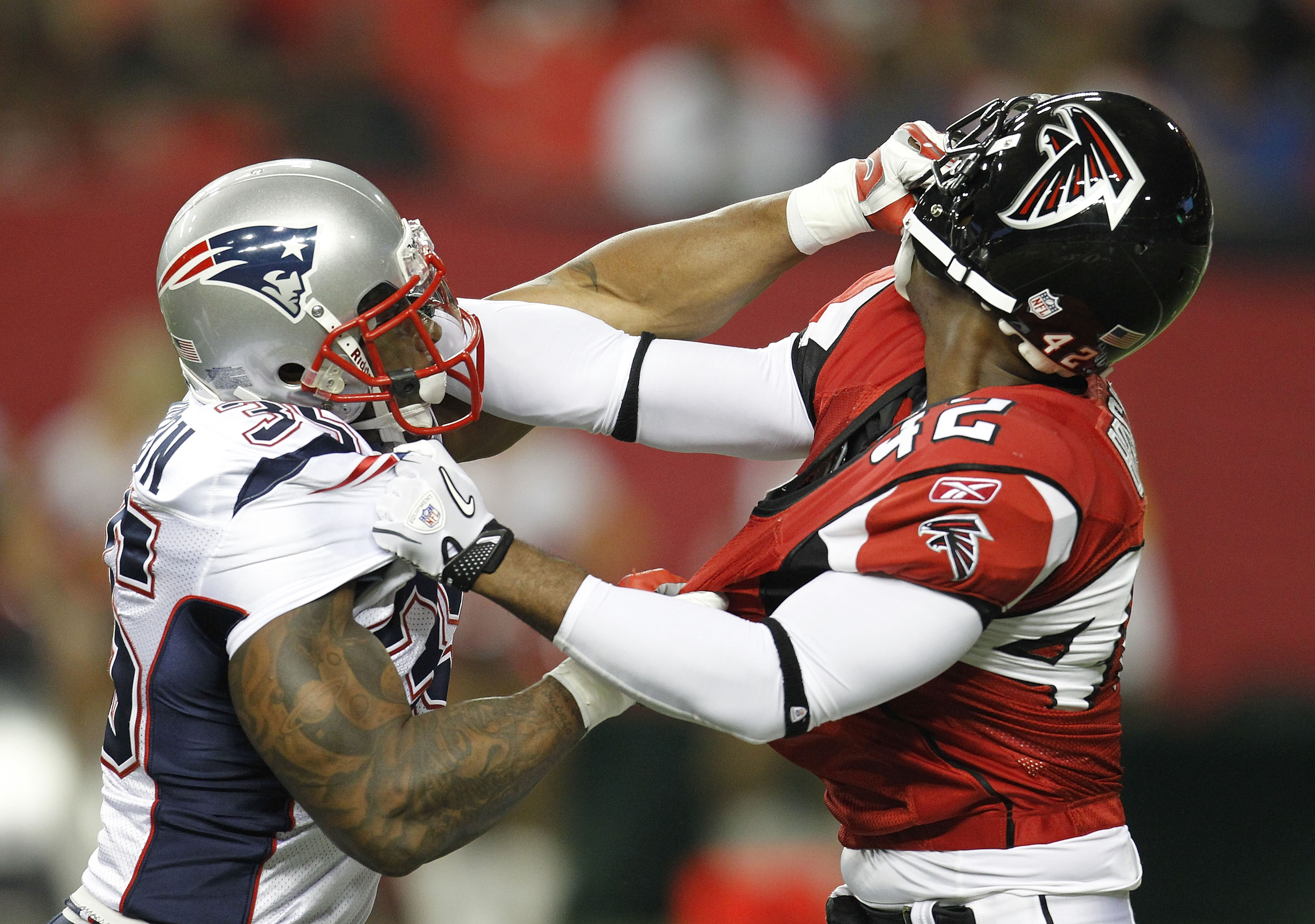 ATLANTA - AUGUST 19:  Safety Eric Brock #42 of the Atlanta Falcons and running back Thomas Clayton #35 of the New England Patriots grab helmets during a special teams play in the preseason game at the Georgia Dome on August 19, 2010 in Atlanta, Georgia.
