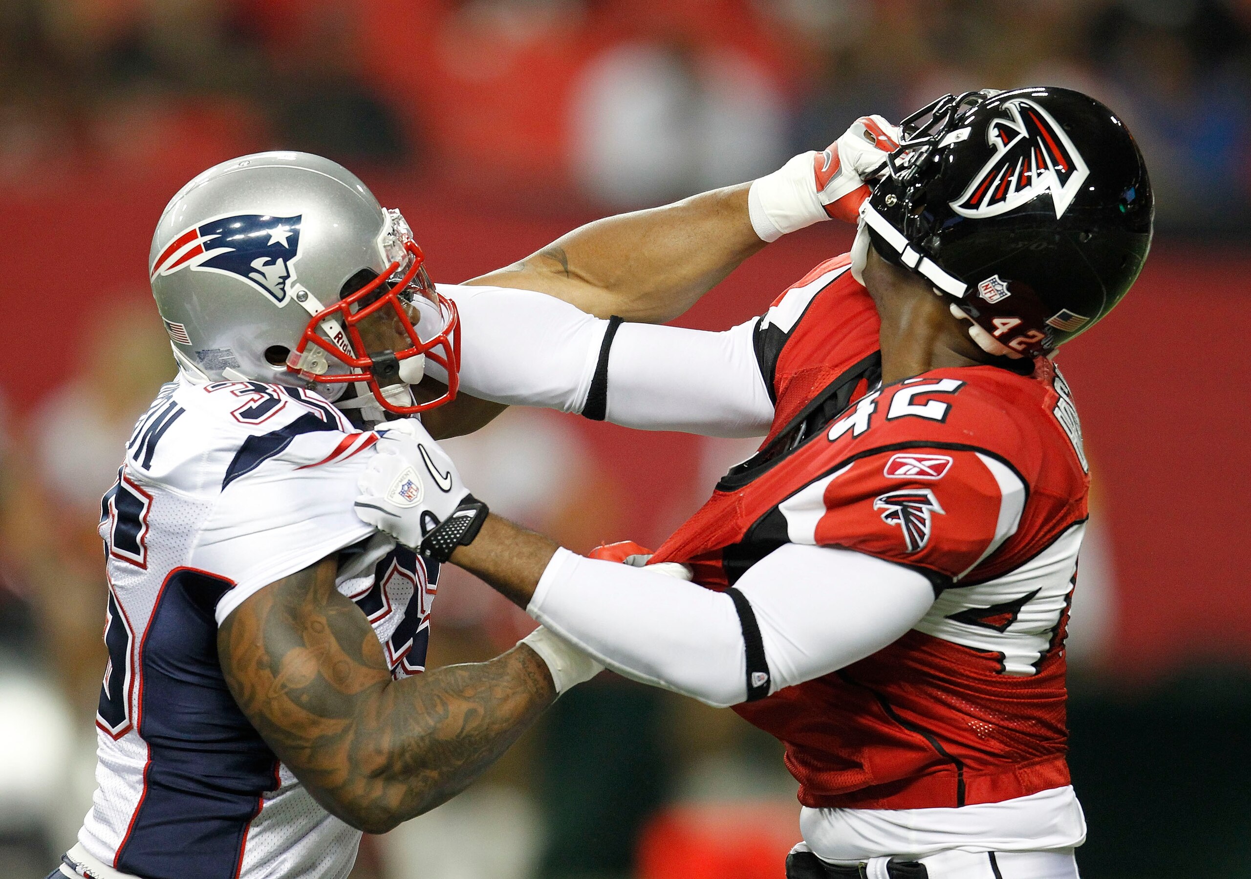 ATLANTA - AUGUST 19:  Safety Eric Brock #42 of the Atlanta Falcons and running back Thomas Clayton #35 of the New England Patriots grab helmets during a special teams play in the preseason game at the Georgia Dome on August 19, 2010 in Atlanta, Georgia.