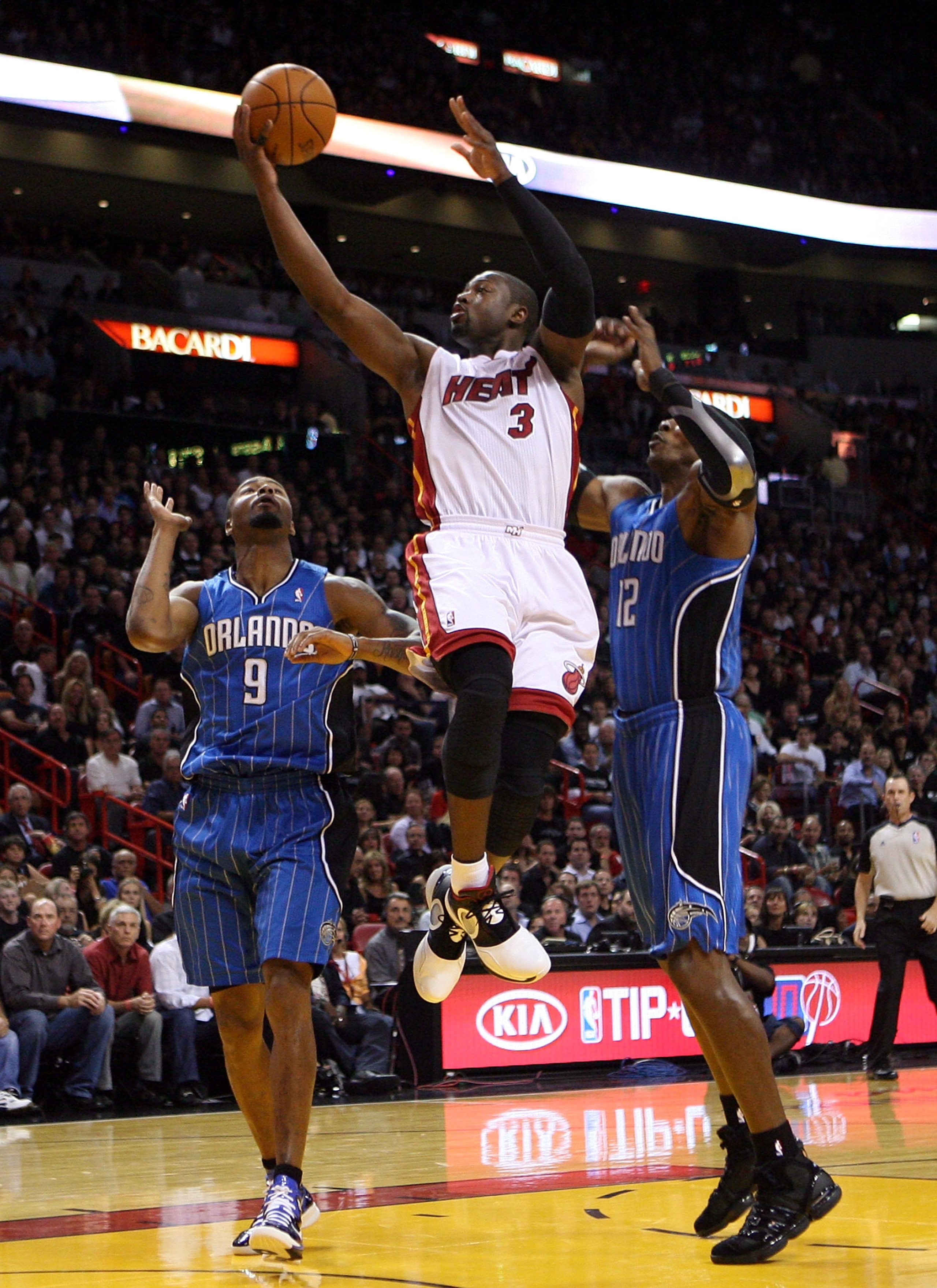 MIAMI - OCTOBER 29:  Guard Dwyane Wade #3 of  the Miami Heat shoots against Rashard Lewis #9 and Dwight Howard #12  of the Orlando Magic at American Airlines Arena on October 29, 2010 in Miami, Florida.  NOTE TO USER: User expressly acknowledges and agree