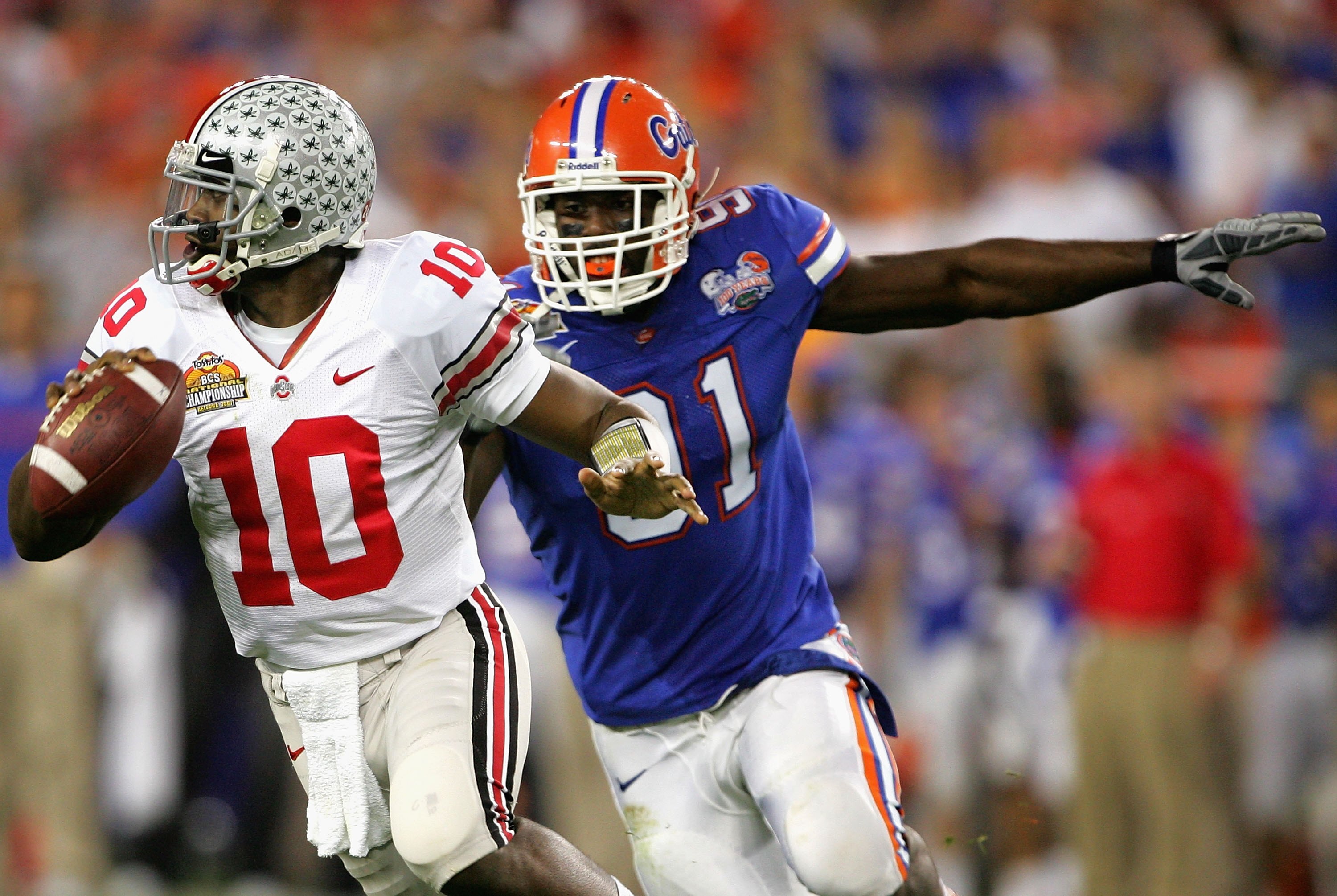 GLENDALE, AZ - JANUARY 08:  Quarterback Troy Smith #10 of the Ohio State Buckeyes scrambles with the ball under pressure from Derrick Harvey #91 of the Florida Gators during the 2007 Tostitos BCS National Championship Game at the University of Phoenix Sta