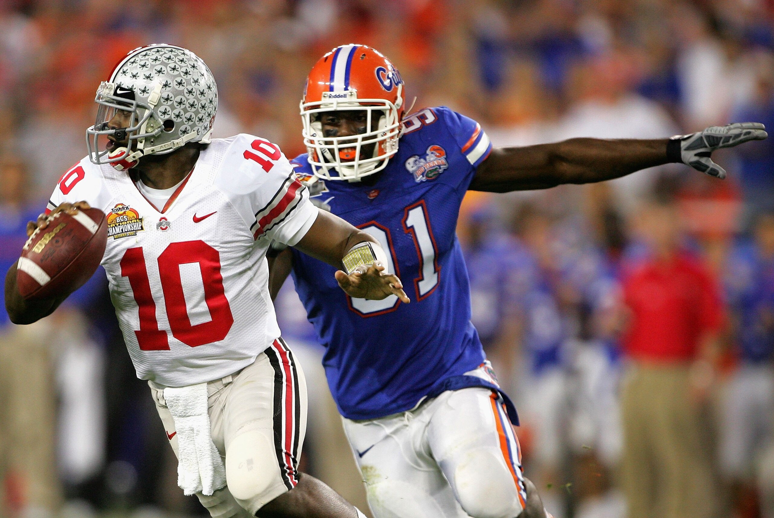 GLENDALE, AZ - JANUARY 08:  Quarterback Troy Smith #10 of the Ohio State Buckeyes scrambles with the ball under pressure from Derrick Harvey #91 of the Florida Gators during the 2007 Tostitos BCS National Championship Game at the University of Phoenix Sta