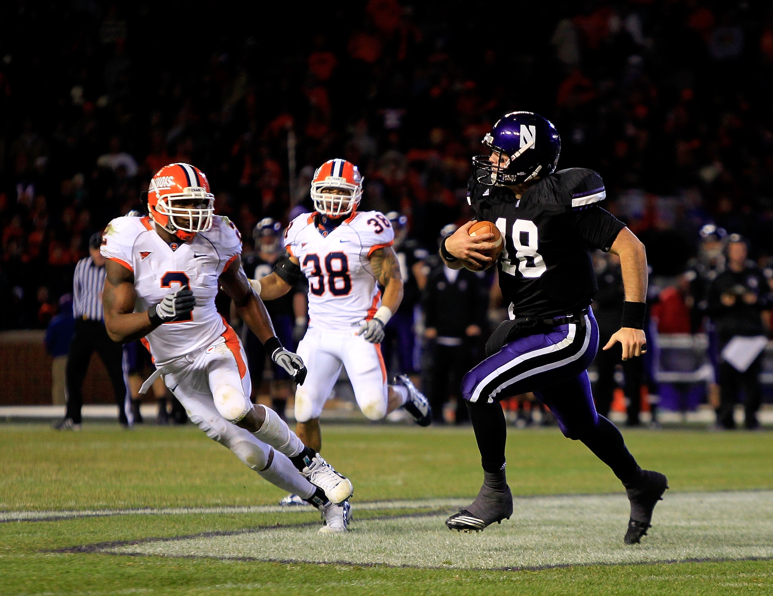 CHICAGO - NOVEMBER 20: Evan Watkins #18 of the Northwestern Wildcats runs for a first down pursued by Travon Wilson #3 and Ian Thomas #38 of the Illinois Fighting Illini during a game played at Wrigley Field on November 20, 2010 in Chicago, Illinois. Illi