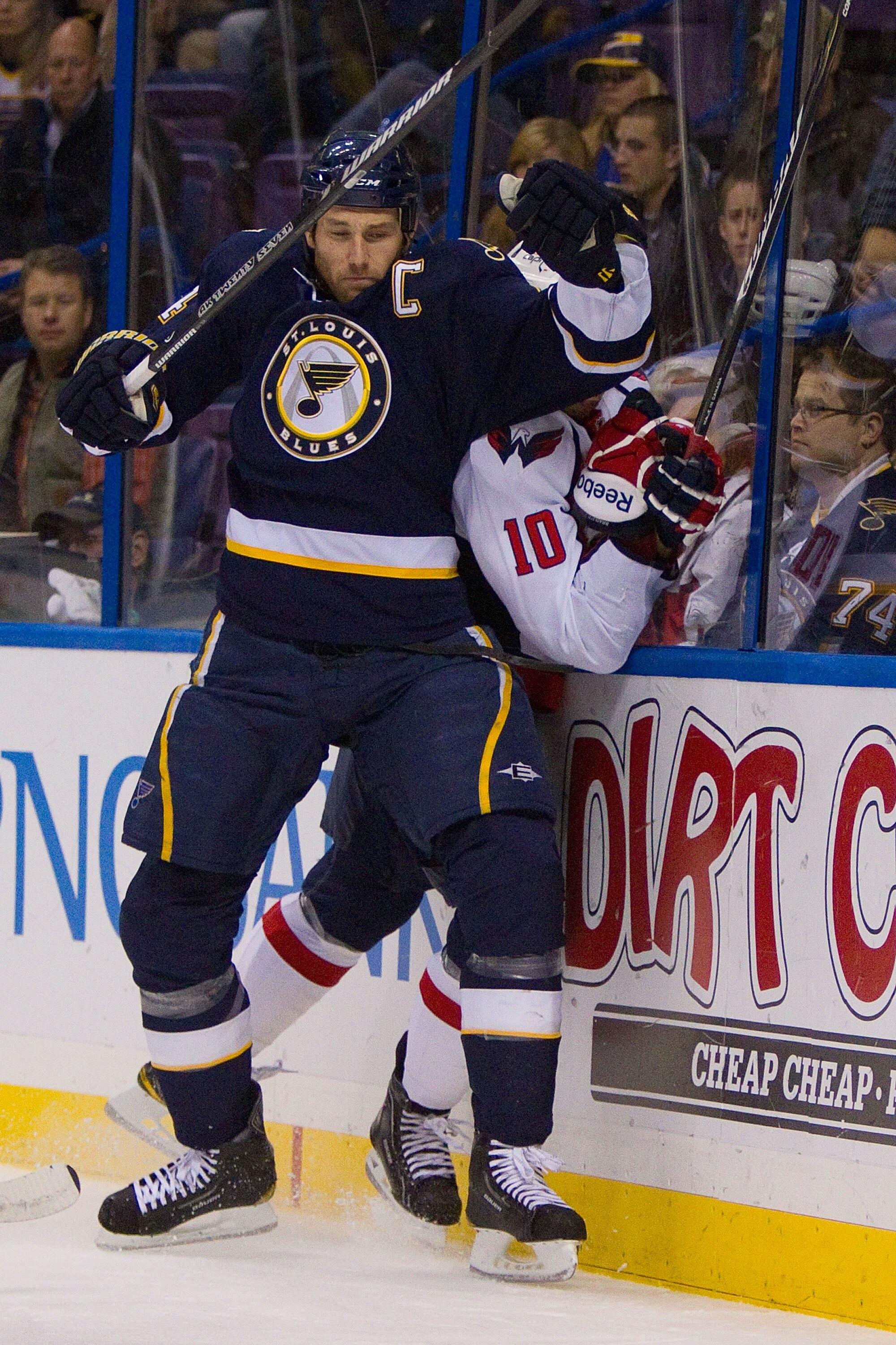 ST. LOUIS, MO - DECEMBER 01: Eric Brewer #4 of the St. Louis Blues checks Matt Bradley #10 of the Washington Capitals into the boards at the Scottrade Center on December 1, 2010 in St. Louis, Missouri.  (Photo by Dilip Vishwanat/Getty Images)
