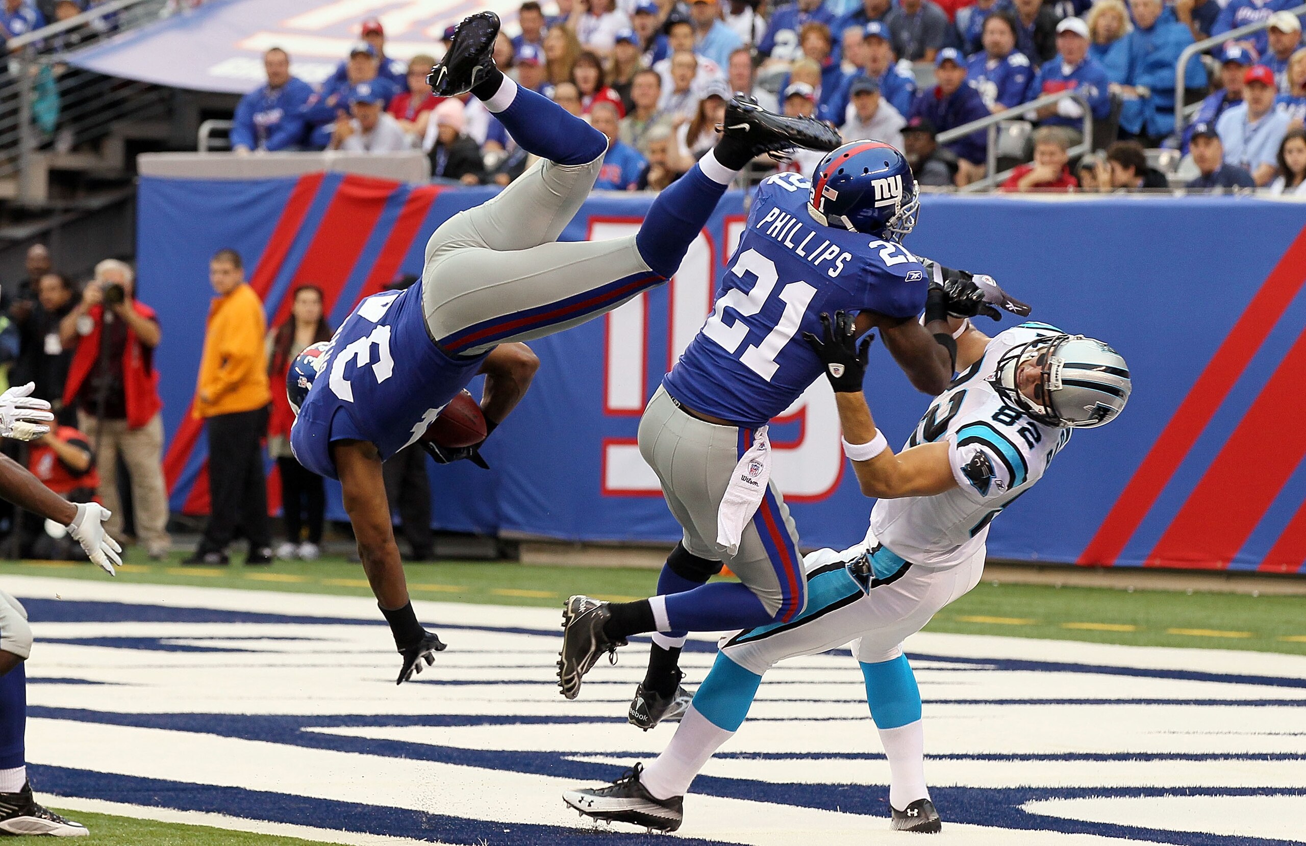 EAST RUTHERFORD, NJ - SEPTEMBER 12:  Deon Grant #34 of the New York Giants intercepts a pass in the endzone intended for Gary Barnidge #82 of the Carolina Panthers as teammate Kenny Phillips #21 defends during the first quarter on September 12, 2010 at th