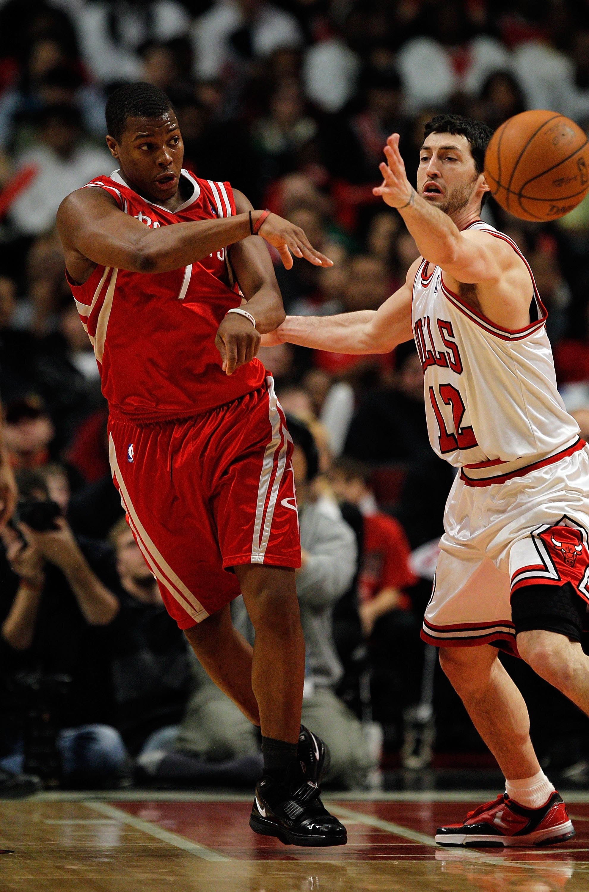 CHICAGO - MARCH 22: Kyle Lowery #7 of the Houston Rockets passes the ball under pressure from Kirk Hinrich #12 of the Chicago Bulls at the United Center on March 22, 2010 in Chicago, Illinois. The Bulls defeated the Rockets 98-88. NOTE TO USER: User expre