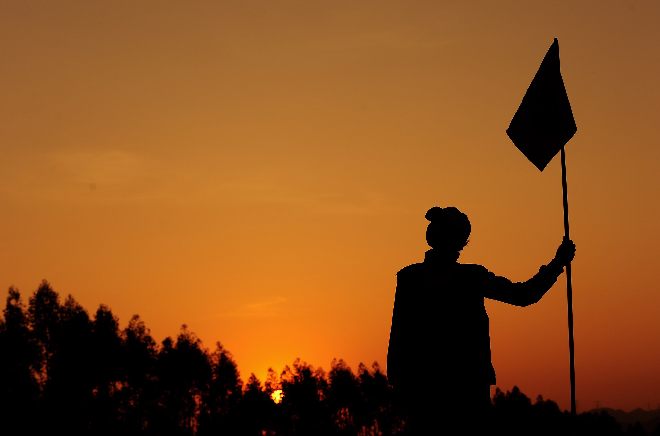 SHENZHEN, CHINA - NOVEMBER 21:  A caddie tends the flag as the sunsets on the Pete Dye course at the MidValley golf complex on November 21, 2009 in Shenzhen, China.  (Photo by Stuart Franklin/Getty Images)