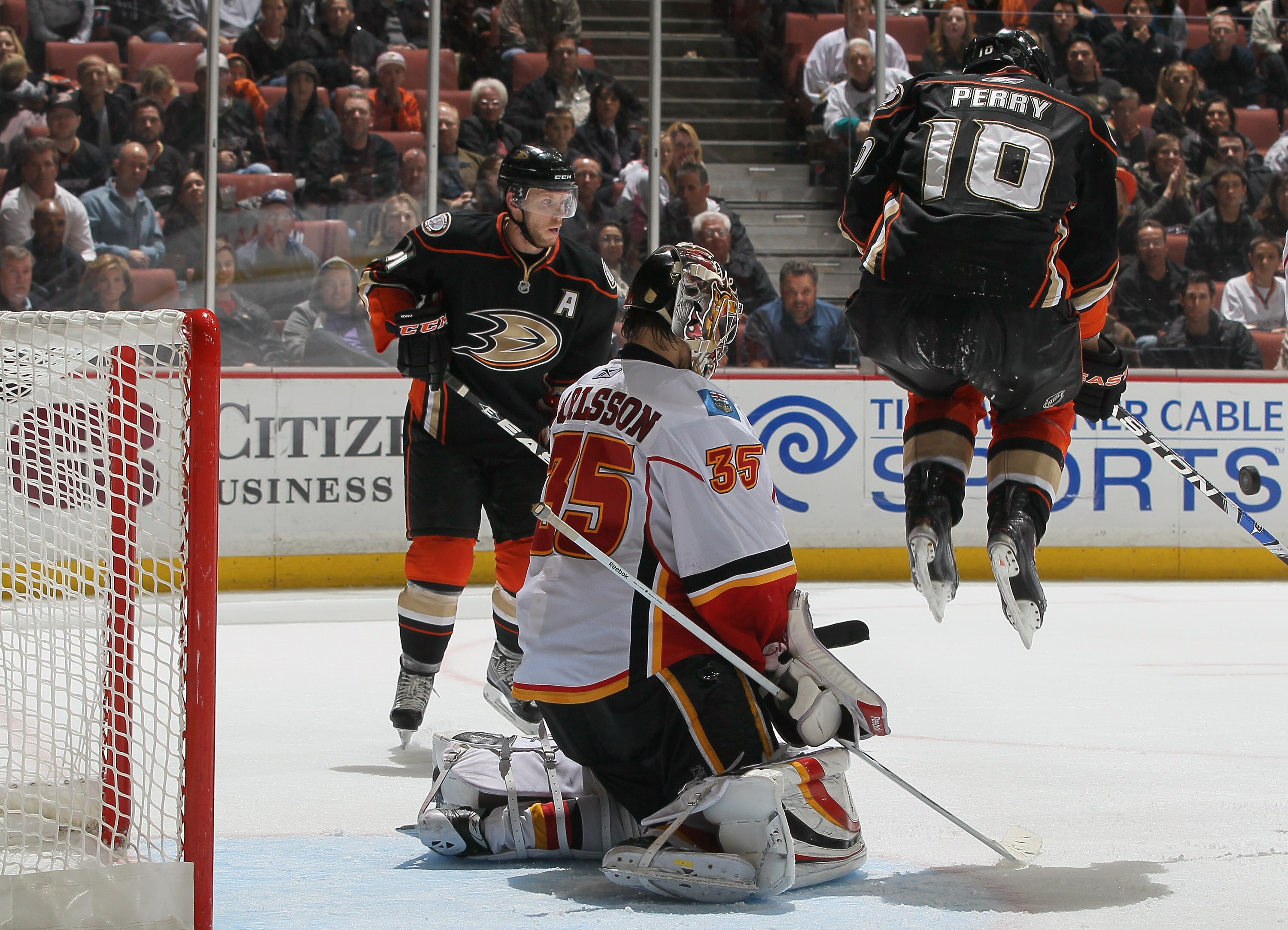 ANAHEIM, CA - DECEMBER 10:  (L-R) Corey Perry #10 of the Anaheim Ducks jumps to deflect the puck as goaltender Henrik Karlsson #35 of the Calgary Flames defends his net  in the third period at the Honda Center on December 10, 2010 in Anaheim, California.
