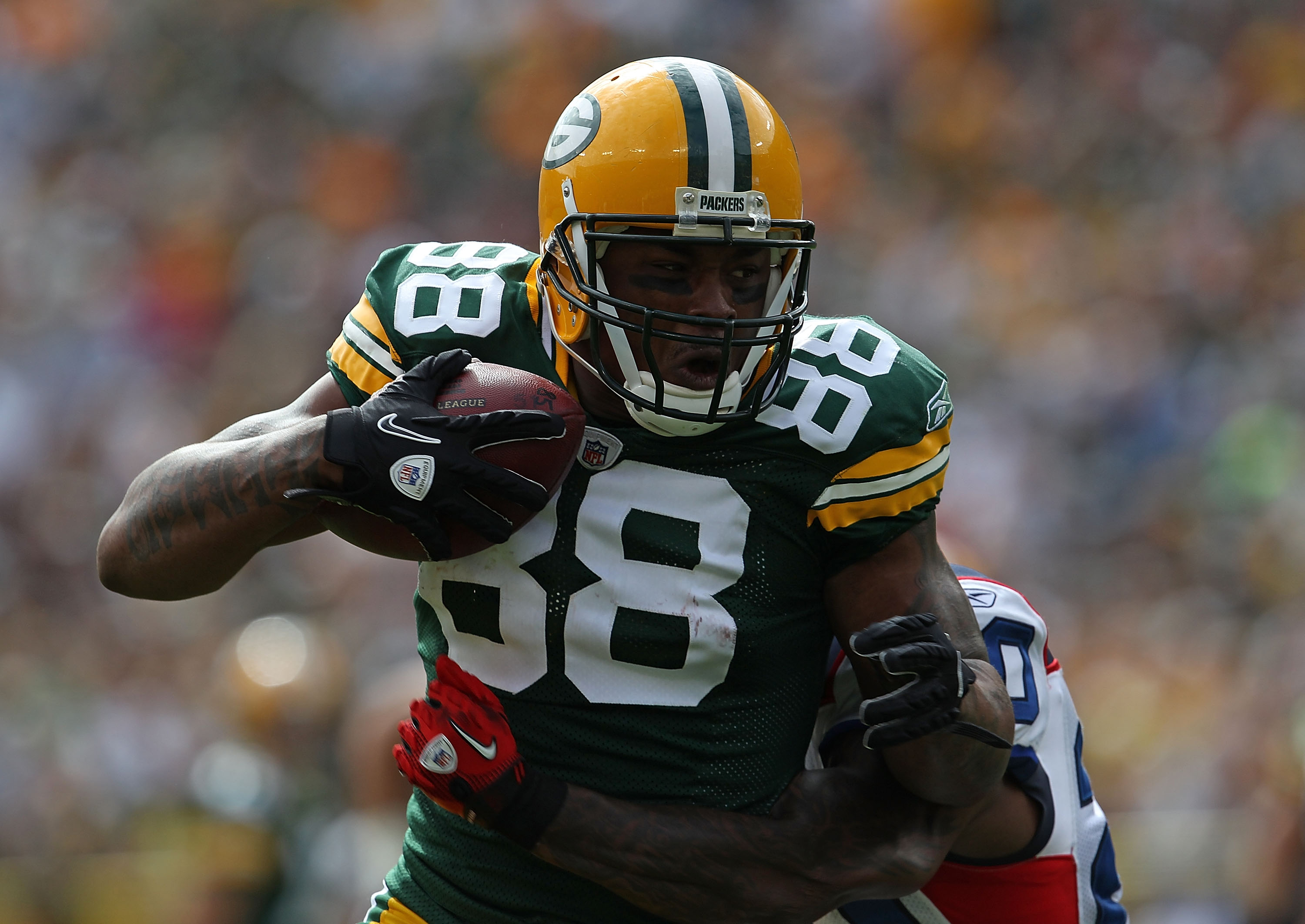 GREEN BAY, WI - SEPTEMBER 19: Jermichael Finley #88 of the Green Bay Packers runs after grabing a pass as Donte Whitner #20 of the Buffalo Bills tries to tackle him at Lambeau Field on September 19, 2010 in Green Bay, Wisconsin. The Packers defeated the B