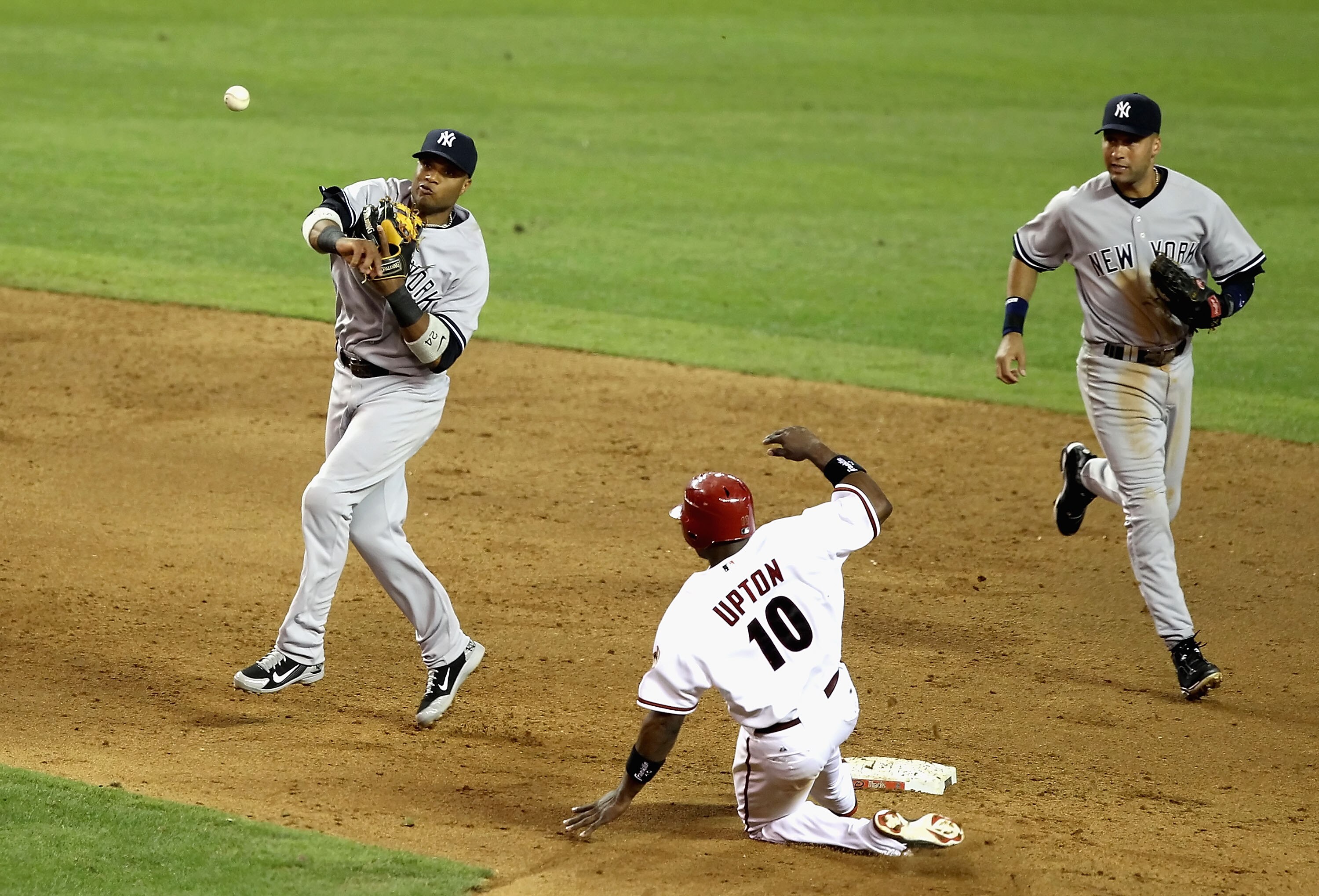 PHOENIX - JUNE 21:  Infielder Robinson Cano #24 of the New York Yankees throws over the sliding Justin Upton #10 of the Arizona Diamondbacks to complete a double play during the sixth inning of the Major League Baseball game at Chase Field on June 21, 201