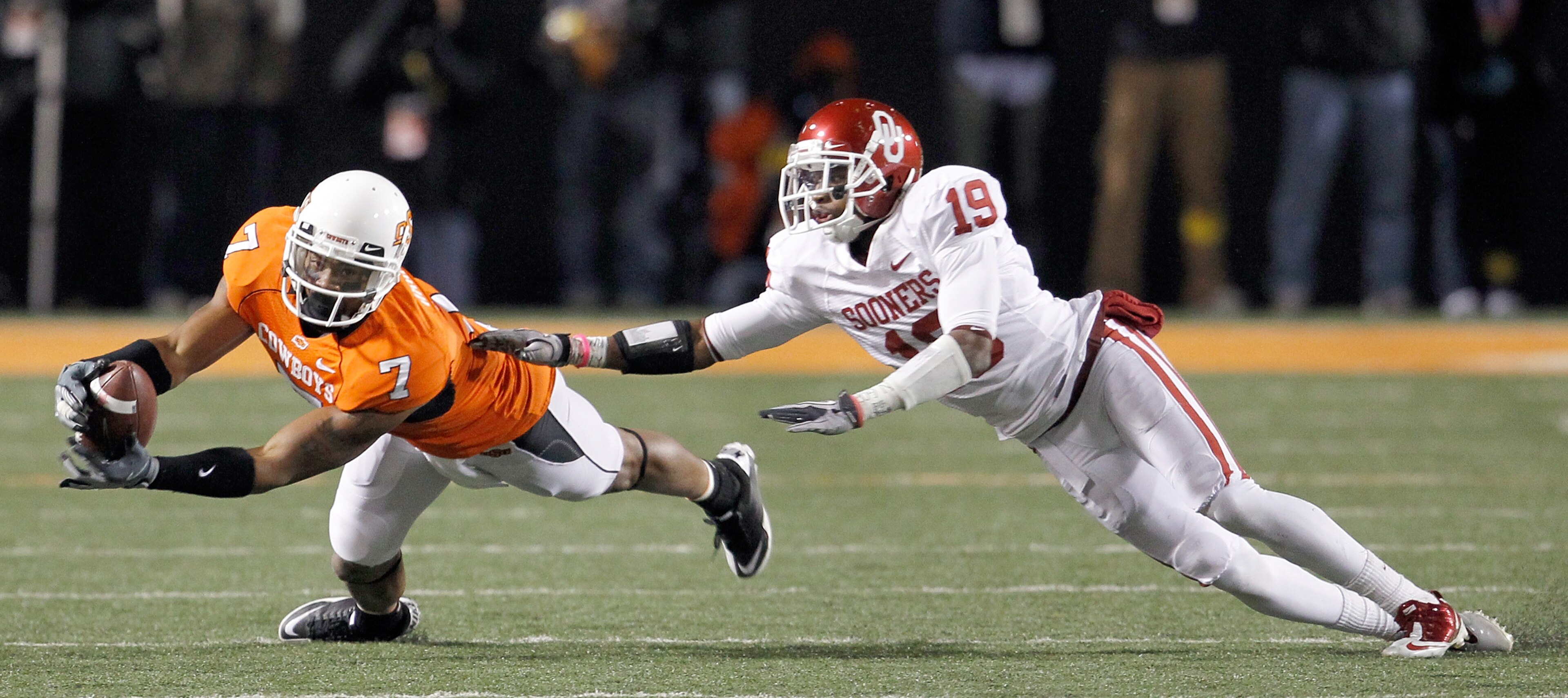 STILLWATER, OK - NOVEMBER 27:  Receiver Michael Harrison #7 of the Oklahoma State Cowboys pulls in a pass against defensive back Demontre Hurst #19 of the Oklahoma Sooners at Boone Pickens Stadium on November 27, 2010 in Stillwater, Oklahoma.  The Sooners