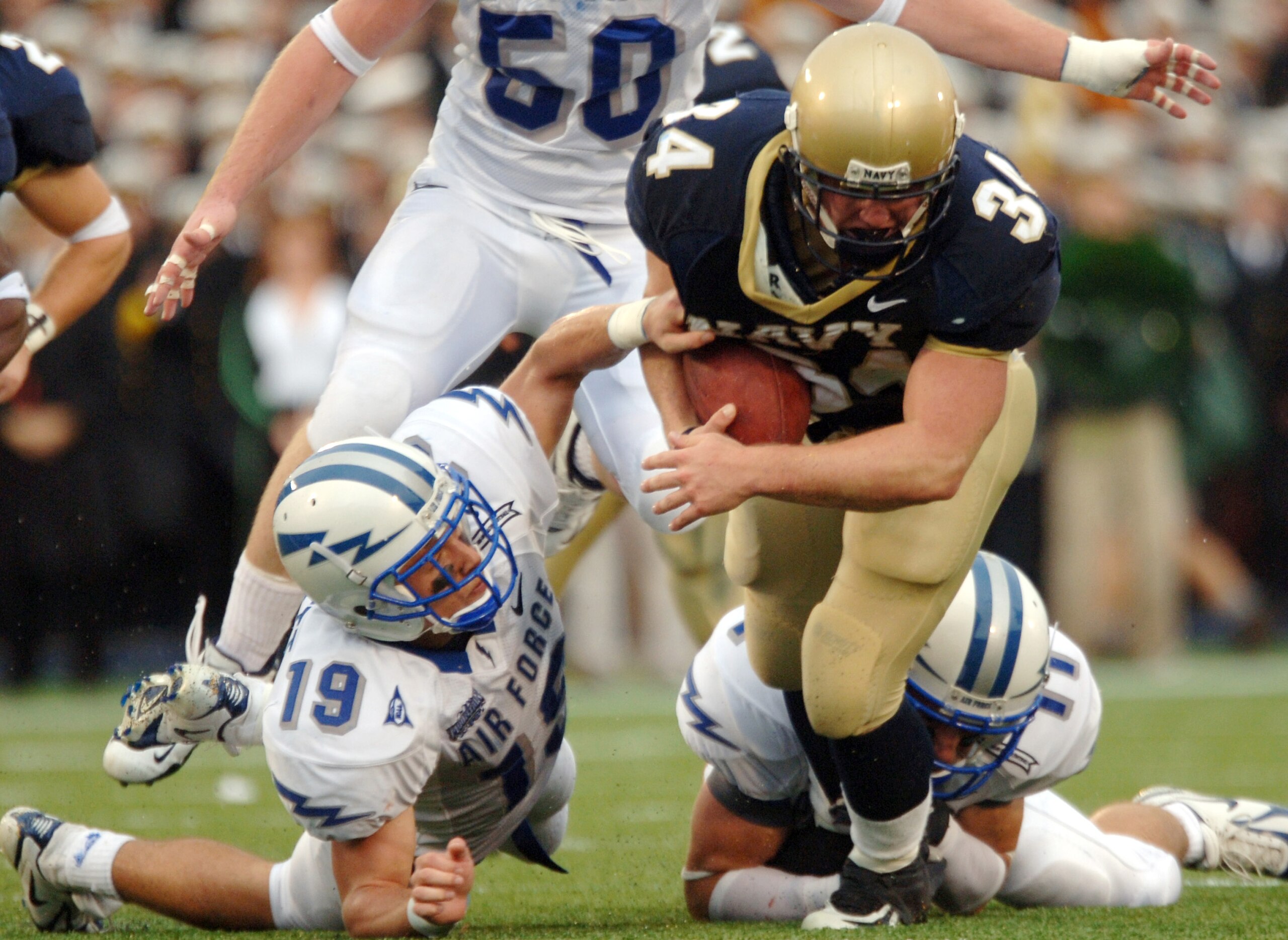 ANNAPOLIS, MD - OCTOBER 8:  In this handout provieded by the U.S. Navy, U.S. Naval Academy Midshipman full back Matt Hall is pulled down by Air Force free safety Ty Paffett #19 and free safety Bobby Giannini #11 during the 2nd quarter of play on October 8