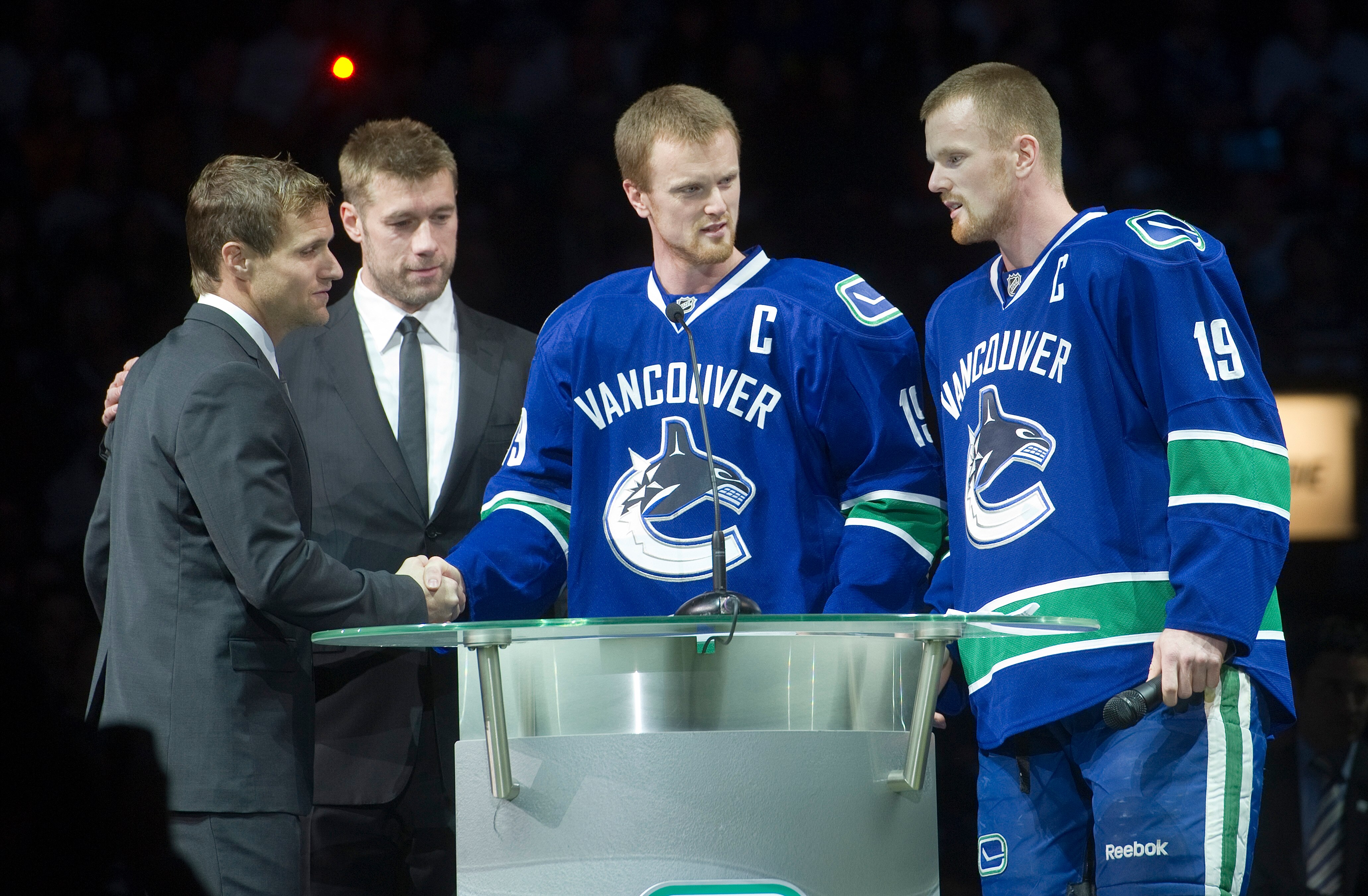 VANCOUVER, CANADA - DECEMBER 11: Henrik Sedin #33 and Daniel Sedin #22 of the Vancouver Canucks along with Mattias Ohlund #5 of the Tampa Bay Lightning greet former Canuck Markus Naslund during a pre-game ceremony to retire Naslund's jersey prior to NHL a