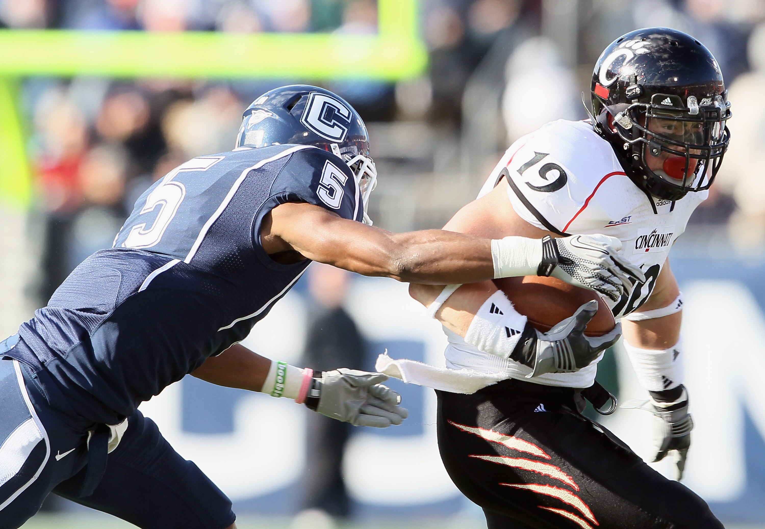 EAST HARTFORD, CT - NOVEMBER 27:  Ben Guidugli #19 of the Cincinnati Bearcats carries the ball as Blidi Wreh-Wilson #5 of the Connecticut Huskies makes the tackle on November 27, 2010 at Rentschler Field in East Hartford, Connecticut.  (Photo by Elsa/Gett