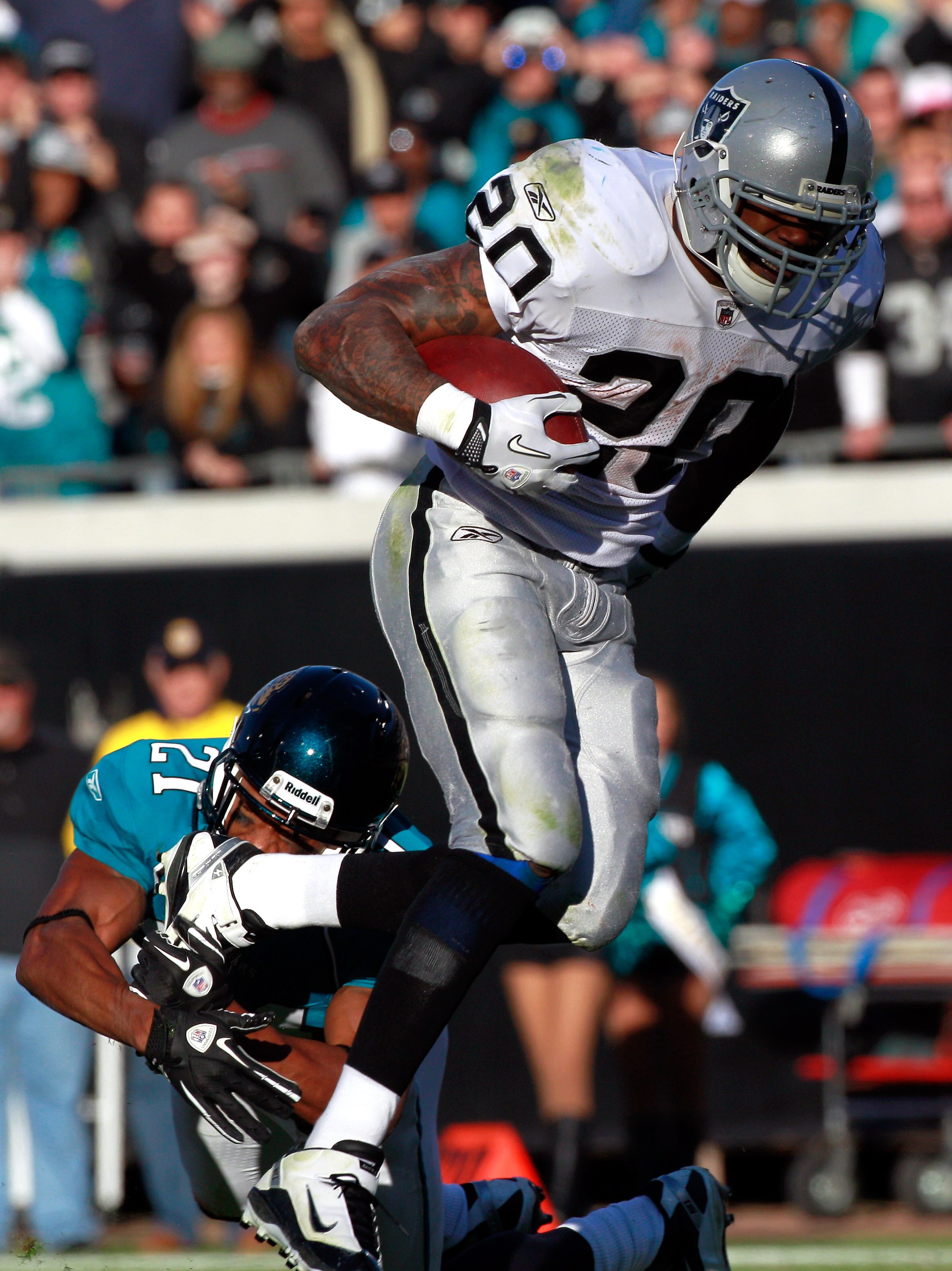 JACKSONVILLE, FL - DECEMBER 12:  Darren McFadden #20 of the Oakland Raiders attempts to break the tackle of Derek Cox #21 of the Jacksonville Jaguars during the game at EverBank Field on December 12, 2010 in Jacksonville, Florida.  (Photo by Sam Greenwood