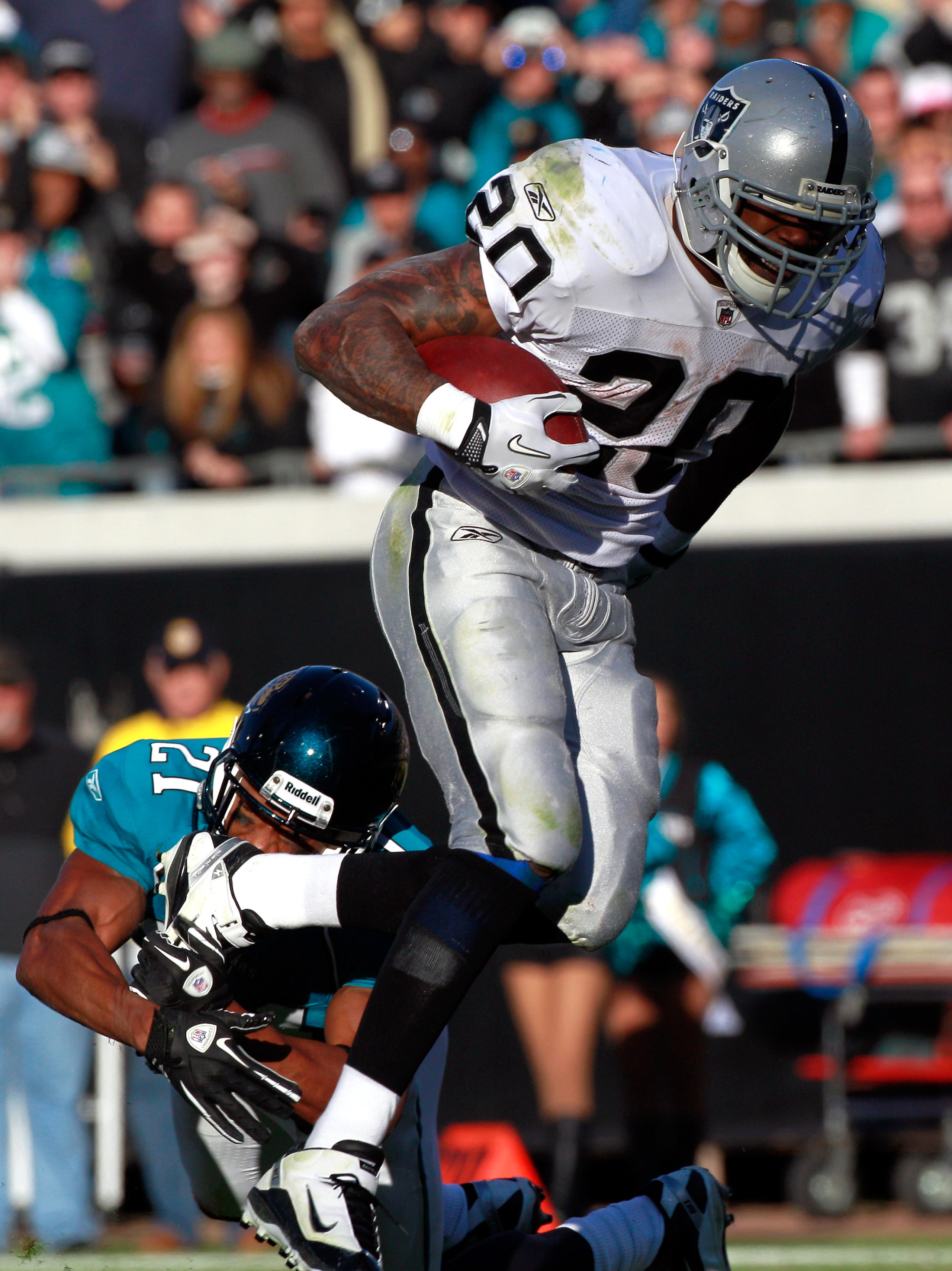 JACKSONVILLE, FL - DECEMBER 12:  Darren McFadden #20 of the Oakland Raiders attempts to break the tackle of Derek Cox #21 of the Jacksonville Jaguars during the game at EverBank Field on December 12, 2010 in Jacksonville, Florida.  (Photo by Sam Greenwood