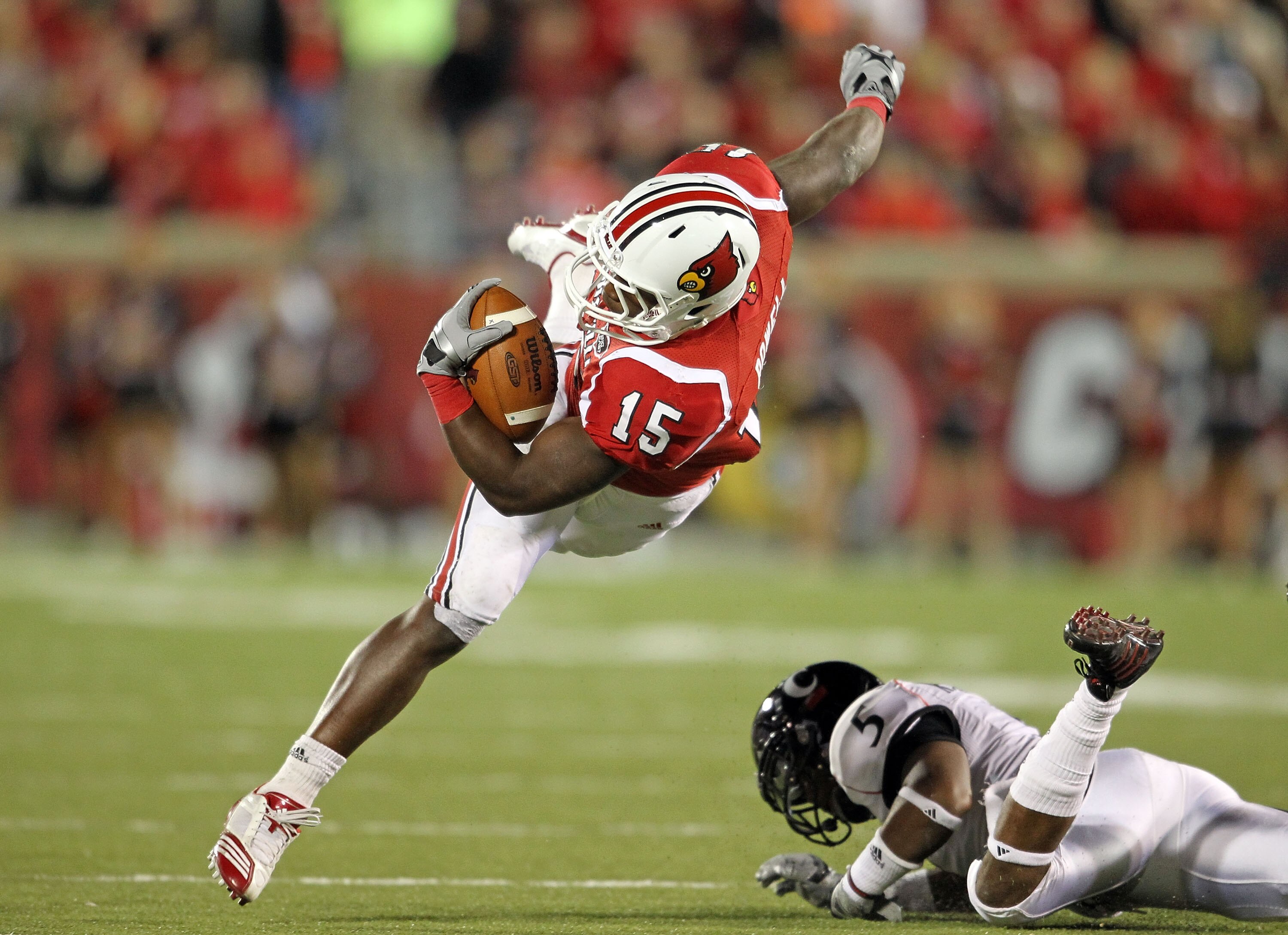 LOUISVILLE, KY - OCTOBER 15:  Bilal Powell #15 of  the Louisville Cardinals runs with the ball while tackled by Reuben Johnson #5 of the Cincinnati Bearcats during the game at Papa John's Cardinal Stadium on October 15, 2010 in Louisville, Kentucky.  (Pho