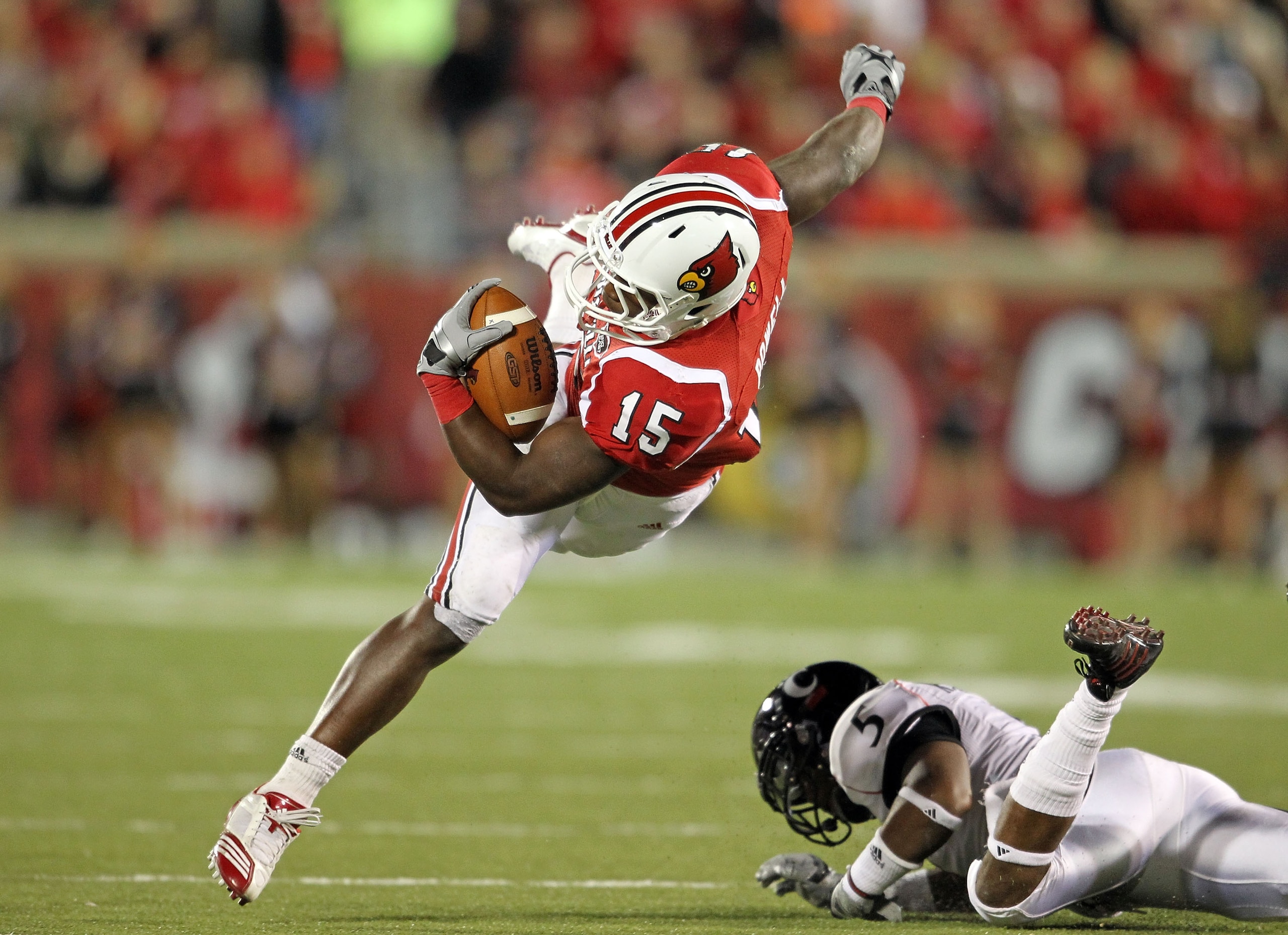 LOUISVILLE, KY - OCTOBER 15: Bilal Powell #15 of the Louisville Cardinals runs with the ball while tackled by Reuben Johnson #5 of the Cincinnati Bearcats during the game at Papa John's Cardinal Stadium on October 15, 2010 in Louisville, Kentucky. (Pho LOUISVILLE, KY - OCTOBER 15: Bilal Powell #15 of the Louisville Cardinals runs with the ball while tackled by Reuben Johnson #5 of the Cincinnati Bearcats during the game at Papa John's Cardinal Stadium on October 15, 2010 in Louisville, Kentucky. (Pho