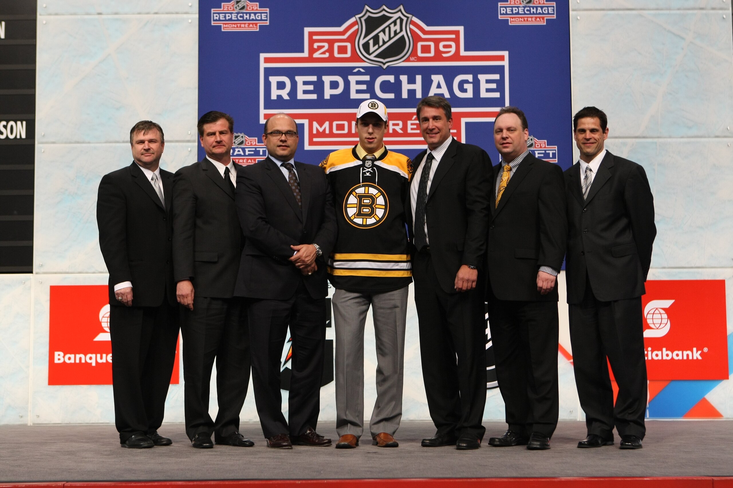 MONTREAL - JUNE 26:  Jordan Caron poses with members of the Boston Bruins organization (L-R) Director of Player Personnel Scott Bradley, Assistant GM Jim Benning, GM Peter Chiarelli, VP Cam Neely, Director of Amateur Scouting Wayne Smith and Director of H