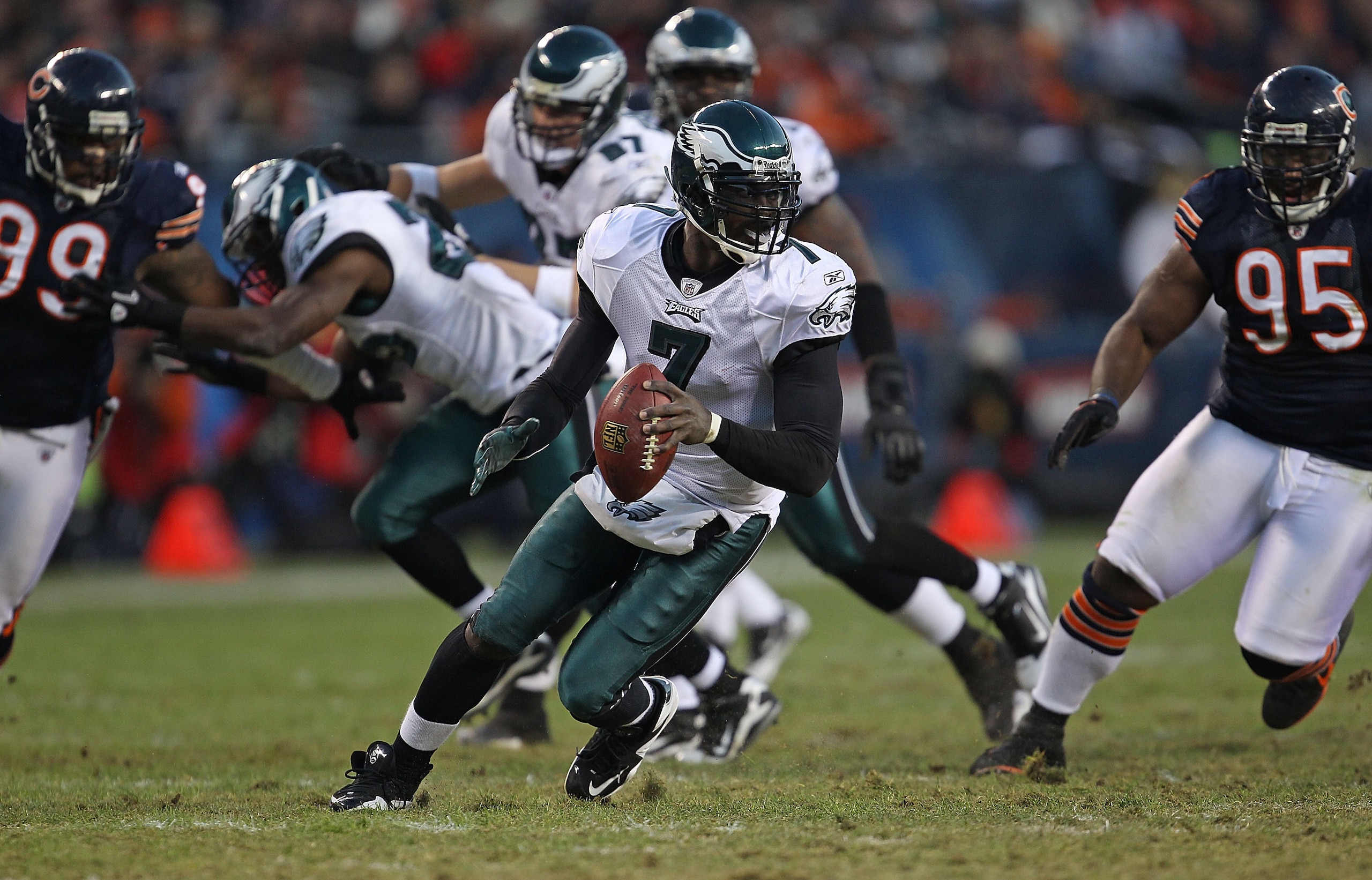 CHICAGO - NOVEMBER 28: Michael Vick #7 of the Philadelphia Eagles runs as he looks for a receiver as Marcus Harrison #99 and Anthony Adams #95 of the Chicago Bears rush at Soldier Field on November 28, 2010 in Chicago, Illinois. The Bears defeated the Eag