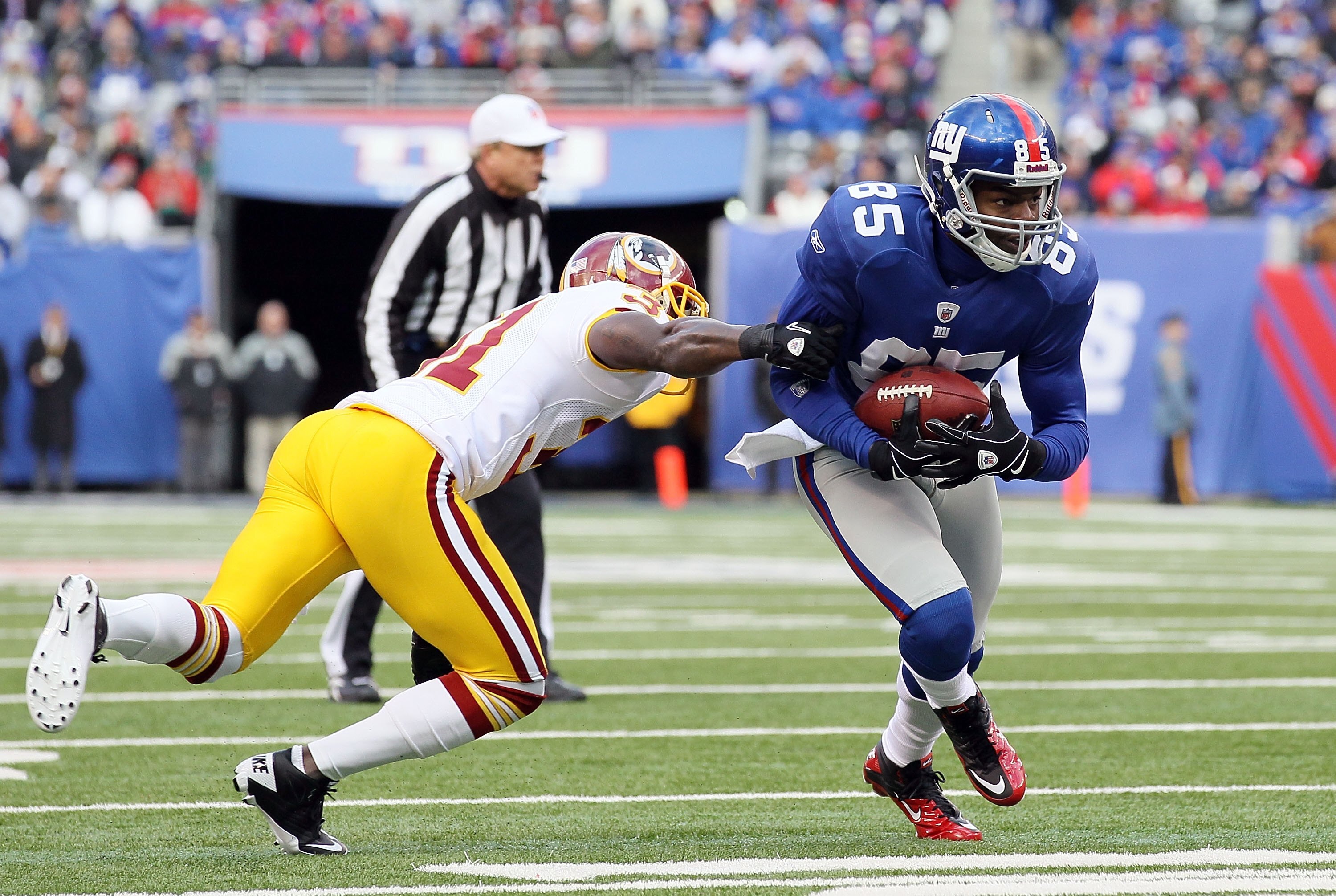 EAST RUTHERFORD, NJ - DECEMBER 05:  Derek Hagan #85 of the New York Giants eludes a tackle from Phillip Buchanon #31 of the Washington Redskins on December 5, 2010 at the New Meadowlands Stadium in East Rutherford, New Jersey.  (Photo by Jim McIsaac/Getty