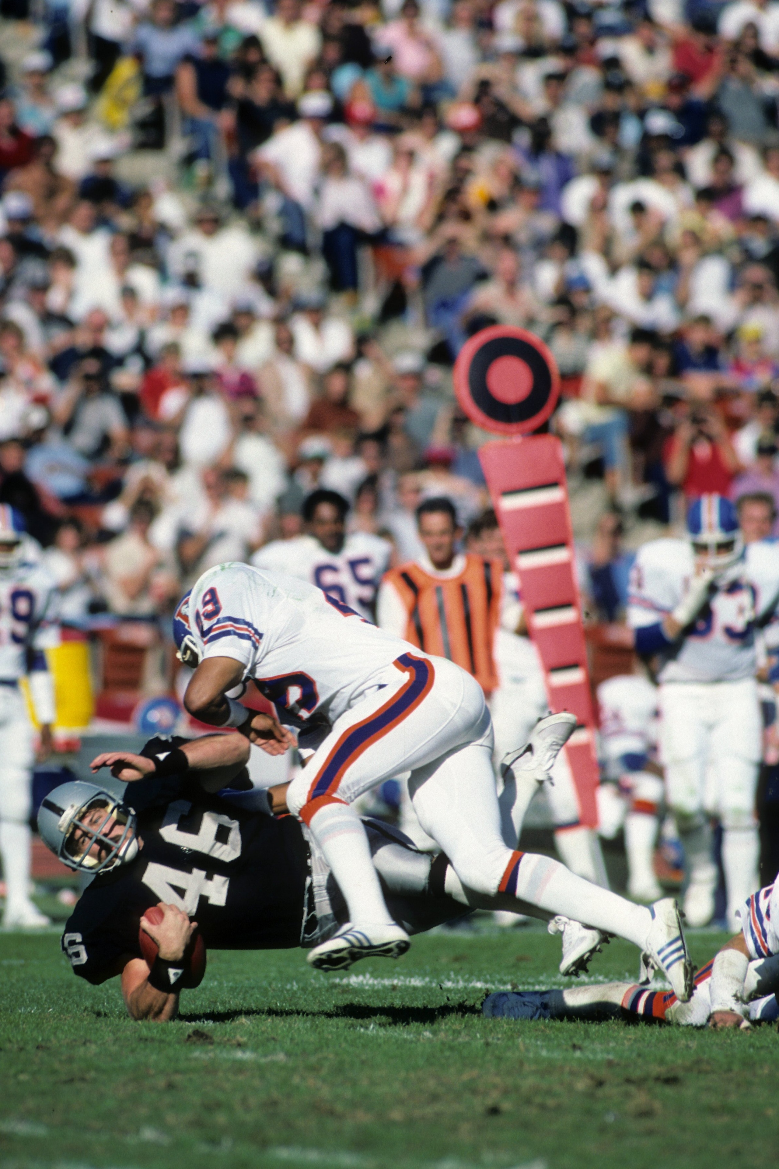 LOS ANGELES, CA - NOVEMBER 13:  Todd Christensen #46 of the Los Angeles Raiders is tackled by Dennis Smith #49 of the Denver Broncos during the game at the Los Angeles Memorial Coliseum on November 13, 1983 in Los Angeles, California.  The Raiders won 22-