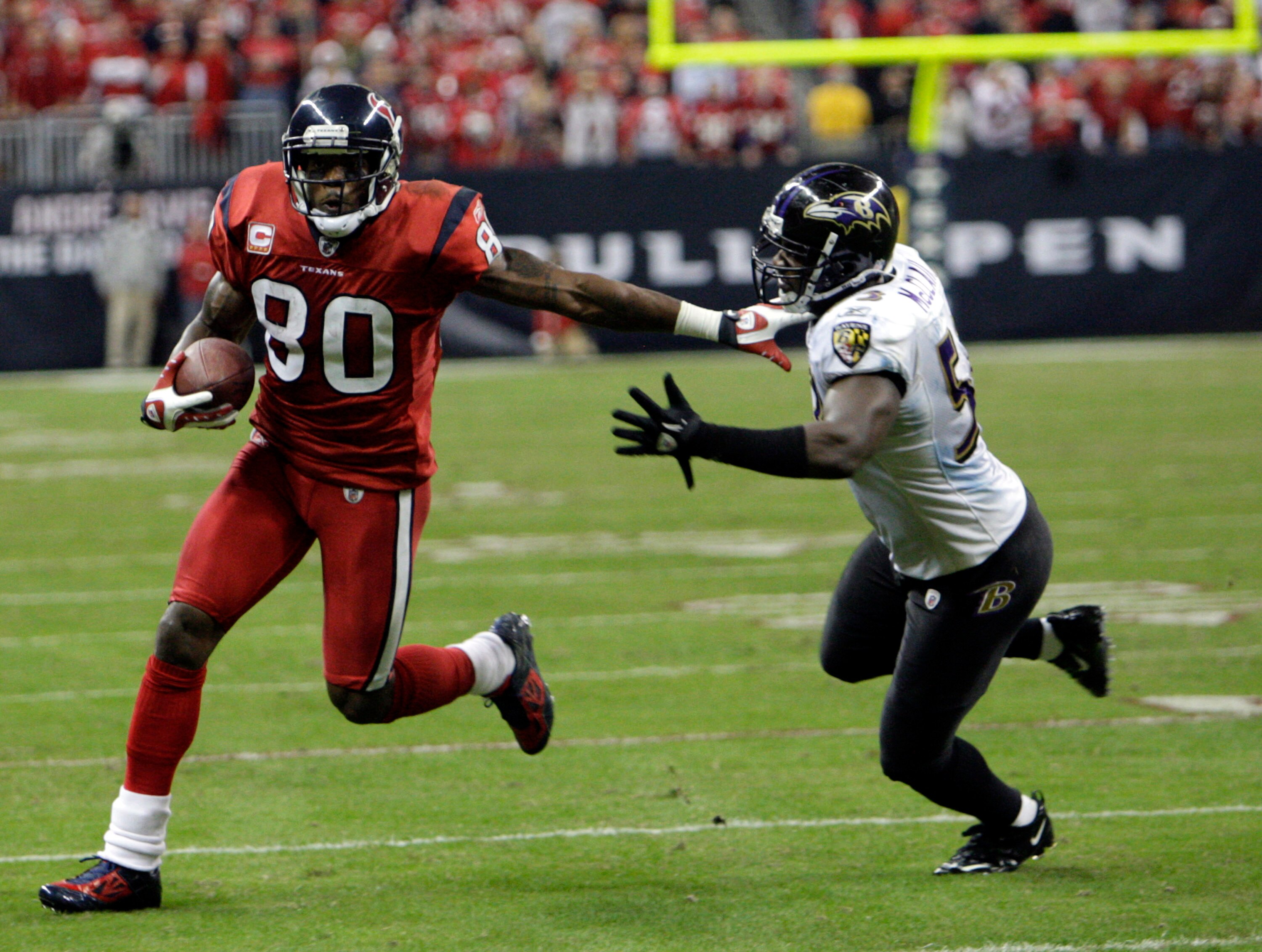HOUSTON, TX - DECEMBER 13:  Wide receiver Andre Johnson #80 of the Houston Texans fends off  linebacker Jameel McClain #63 of the Baltimore Ravens as he gains a first down late in the fourth quarter at Reliant Stadium on December 13, 2010 in Houston, Texa