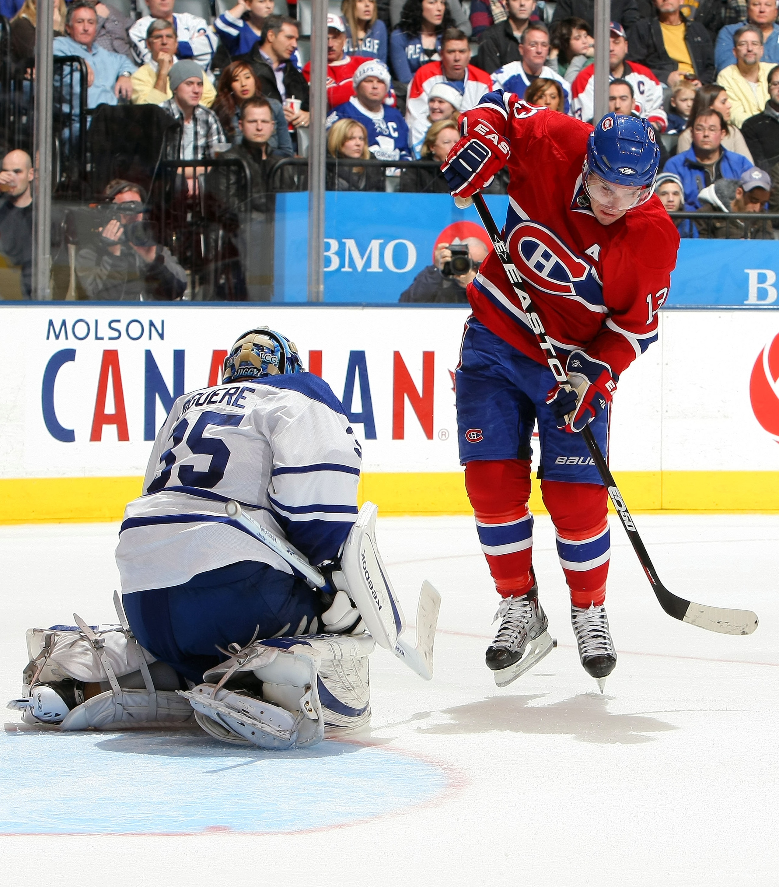 TORONTO - DECEMBER 11:  Mike Cammalleri #13 of the Montreal Canadiens leaps to avoid a shot as Jean-Sebastien Giguere #35 of the Toronto Maple Leafs makes a save during their NHL game at Air Canada Centre on December 11, 2010 in Toronto, Ontario, Canada.(