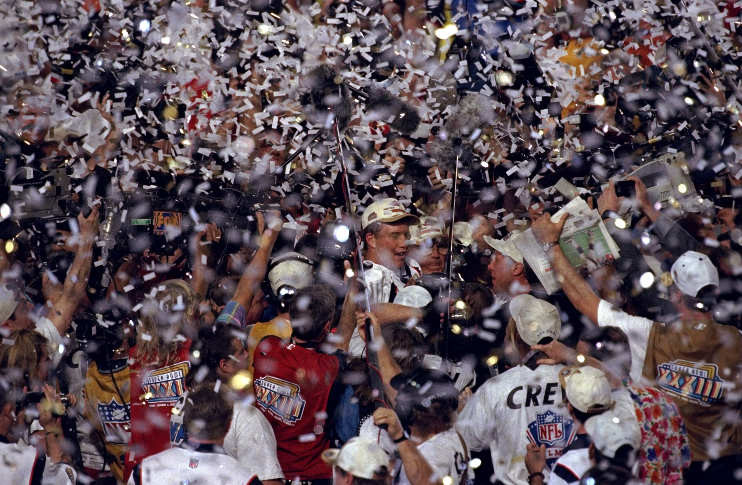 31 Jan 1999: Confetti rains down as quarterback John Elway #7 of the Denver Broncos is mobbed by teammates and fans after defeating the Atlanta Falcons to win Super Bowl XXXIII at Pro Player Stadium in Miami, Florida. The Broncos defeated the Falcons 34-1