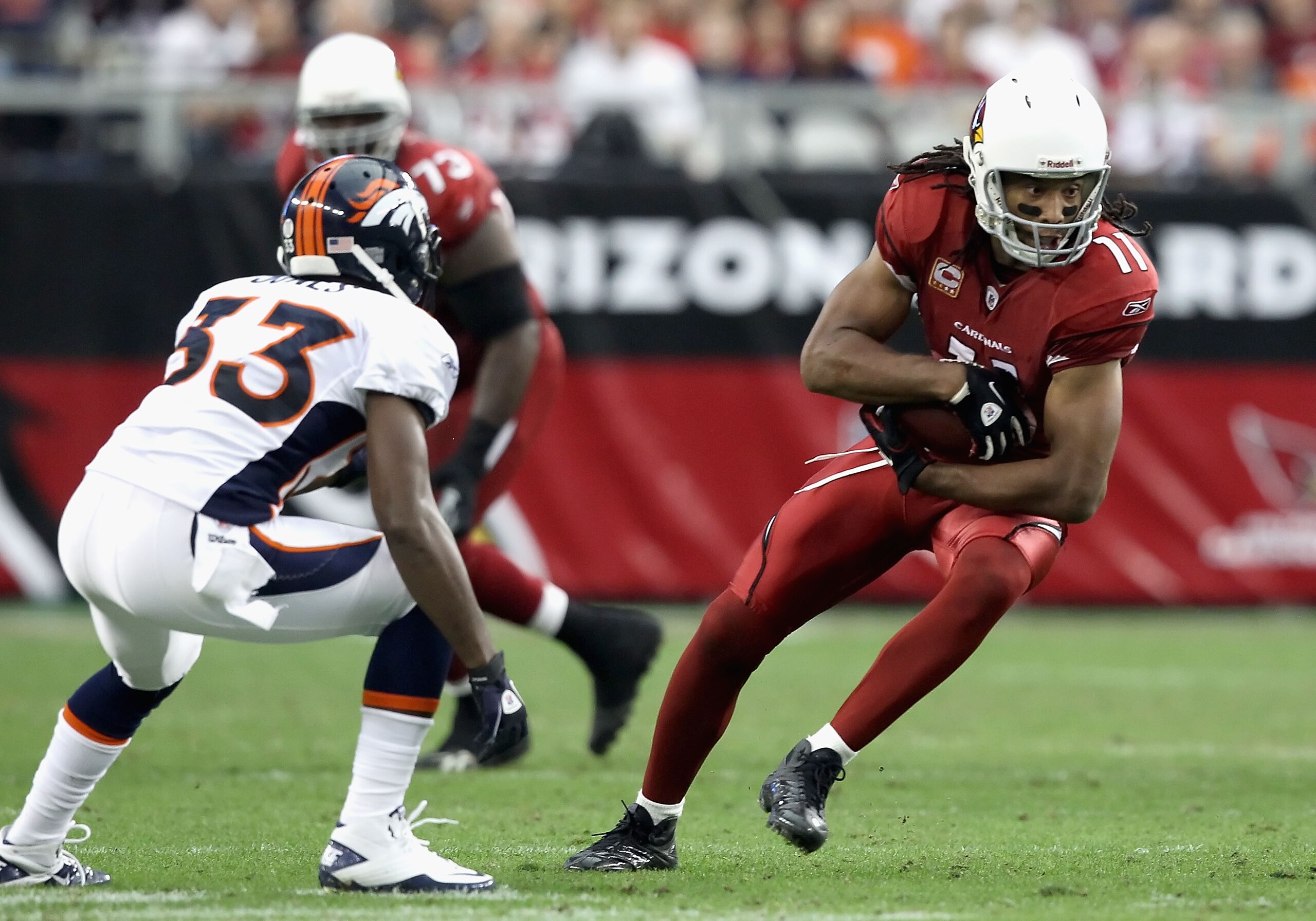 GLENDALE, AZ - DECEMBER 12:  Wide receiver Larry Fitzgerald #11 of the Arizona Cardinals runs with the football after a reception against Nate Jones #33 of the Denver Broncos during the NFL game at the University of Phoenix Stadium on December 12, 2010 in