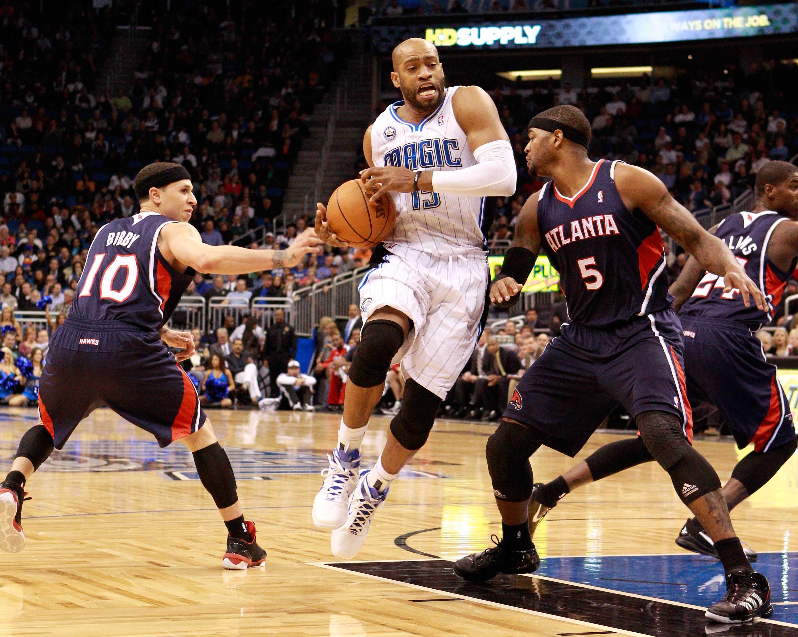 ORLANDO, FL - DECEMBER 06:  Vince Carter #15 of the Orlando Magic drives between Mike Bibby #10 and Josh Smith #5 of the Atlanta Hawks during the game at Amway Arena on December 6, 2010 in Orlando, Florida. NOTE TO USER: User expressly acknowledges and ag