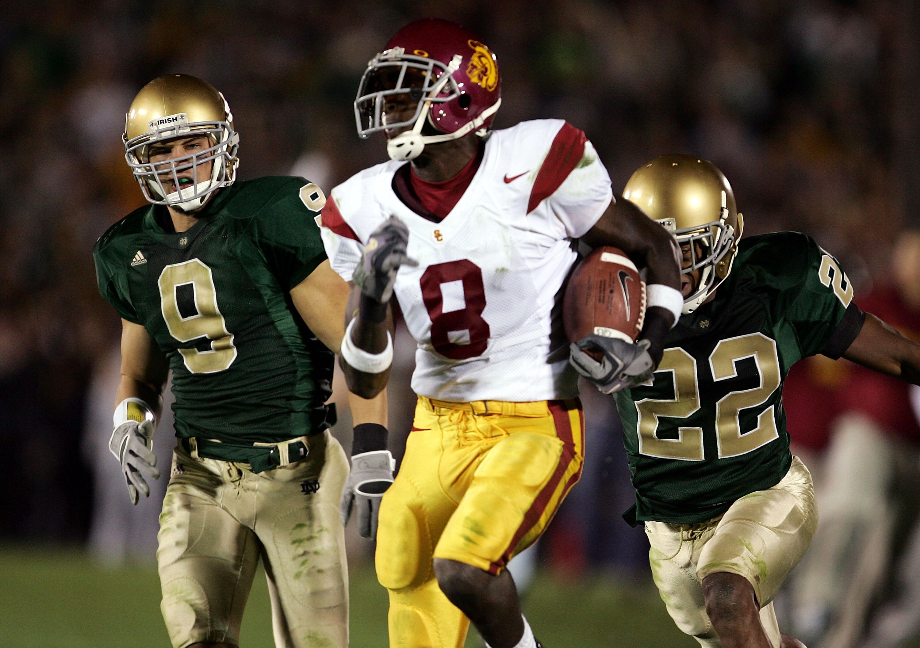 SOUTH BEND, IN - OCTOBER 15:  Dwayne Jarrett #8 of the University of Southern California Trojans sprints away from safety Tom Zbikowski #9 and Ambrose Wooden #22 of the Notre Dame Fighting Irish on October 15, 2005 at Notre Dame Stadium in South Bend, Ind