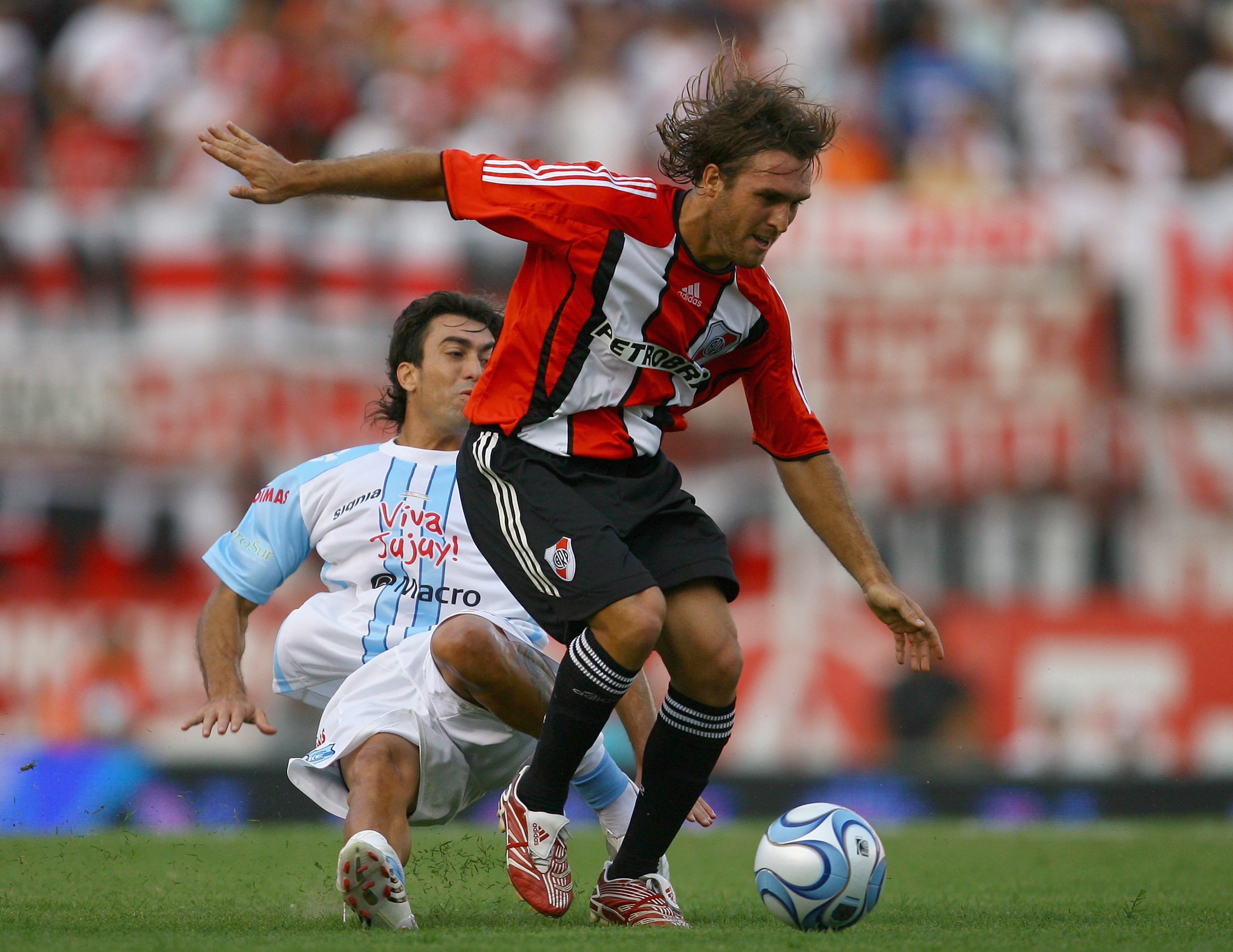 BUENOS AIRES, ARGENTINA - FEBRUARY 10:  Oscar Ahumada of River Plate is challenged by Matias Miramontes of Gimnasia de Jujuy during the Primera Division closing season match between River Plate and Gimnasia de Jujuy at the Estadio Monumental on February 1