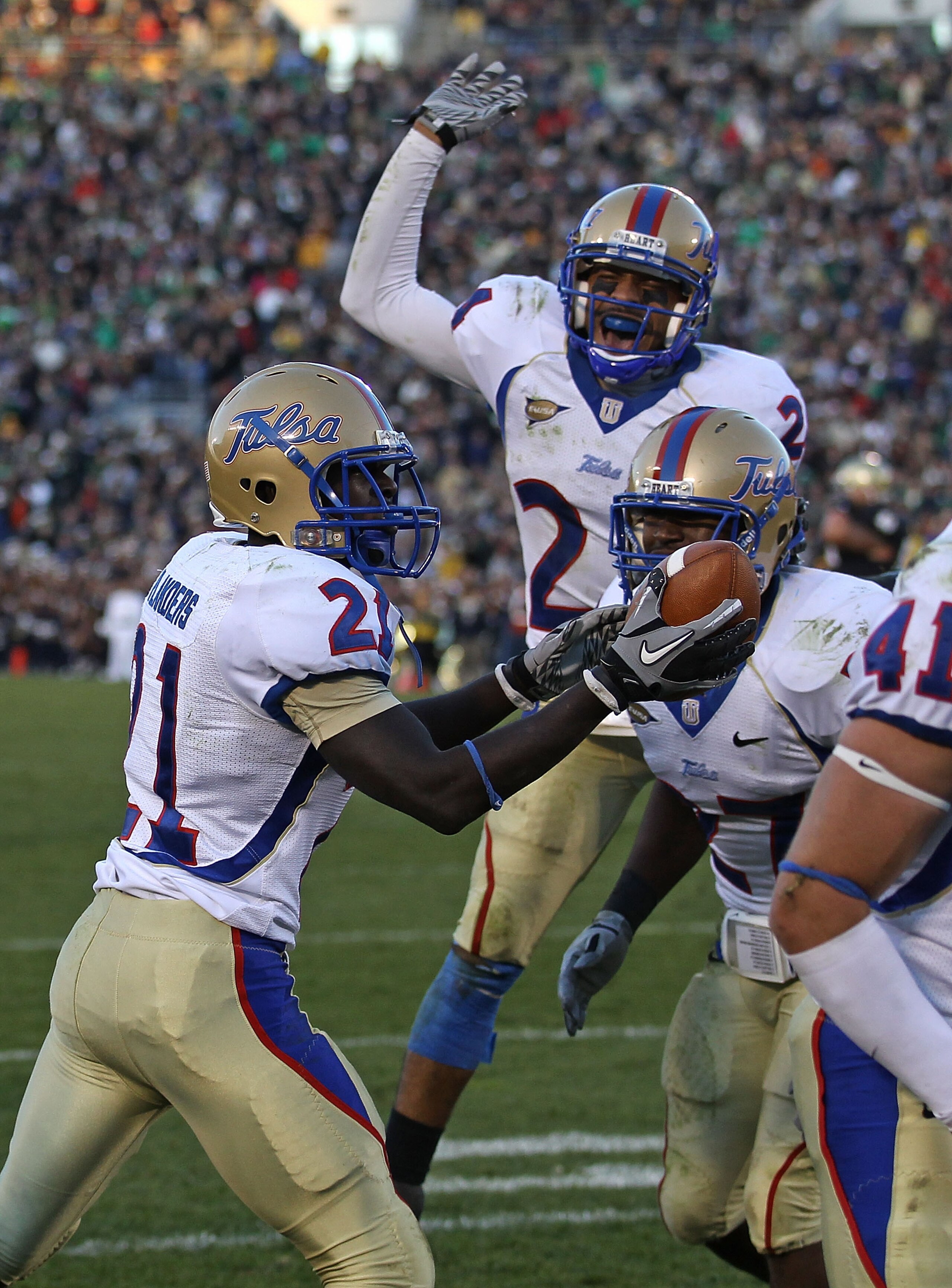 SOUTH BEND, IN - OCTOBER 30: John Flanders #21 of the Tulsa Golden Hurricane holds the ball after intercepting a pass in the end zone against the Notre Dame Fighting Irish as teammates Charles Davis #24 (center) and DeWitt Jennings #27 join the celebratio