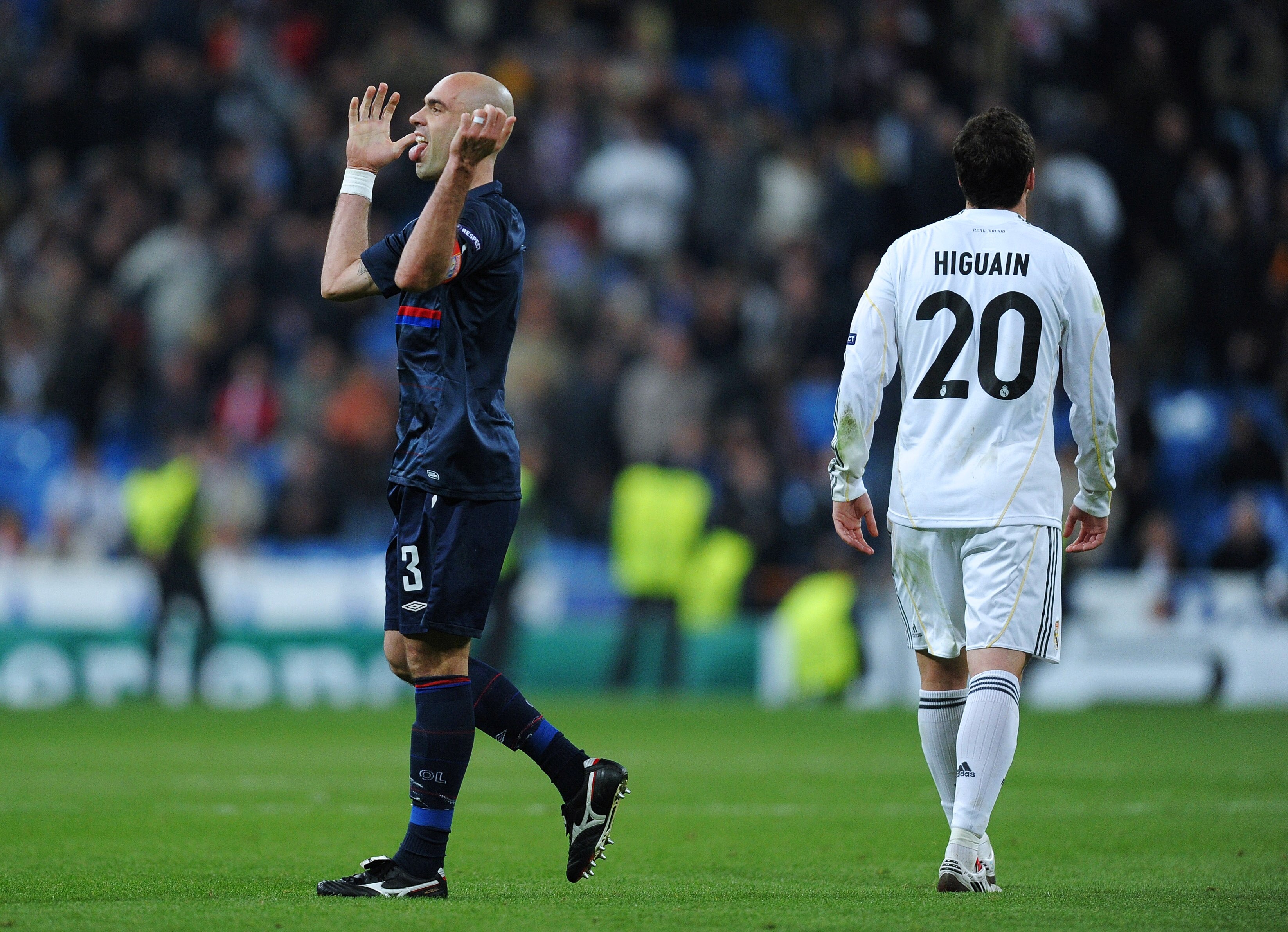 MADRID, SPAIN - MARCH 10:  Cris (L) captain of Lyon celebrates as Gonzalo Higuain of Real Madrid trudges off the pitch during the UEFA Champions League round of 16 second leg match between Real Madrid and Lyon at the Estadio Santiago Bernabeu on March 10,