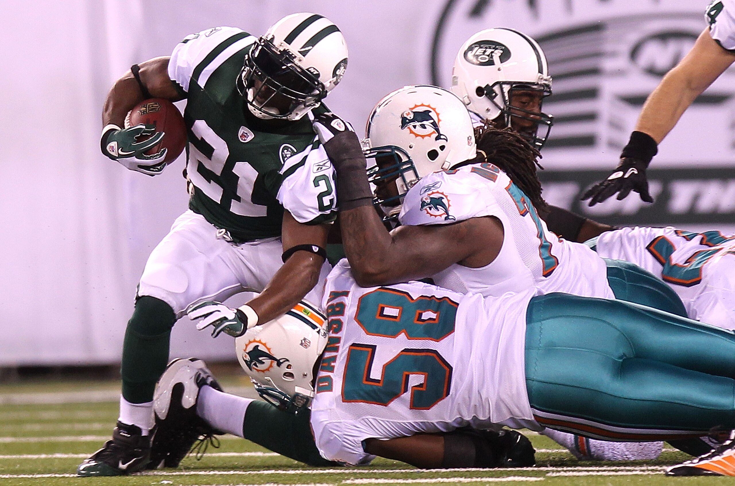 EAST RUTHERFORD, NJ - DECEMBER 12: LaDainian Tomlinson #21 of the New York Jets is tackled by Karlos Dansby #58 and Tony McDaniel #78 of the Miami Dolphins at New Meadowlands Stadium on December 12, 2010 in East Rutherford, New Jersey. (Photo by Nick La EAST RUTHERFORD, NJ - DECEMBER 12: LaDainian Tomlinson #21 of the New York Jets is tackled by Karlos Dansby #58 and Tony McDaniel #78 of the Miami Dolphins at New Meadowlands Stadium on December 12, 2010 in East Rutherford, New Jersey. (Photo by Nick La