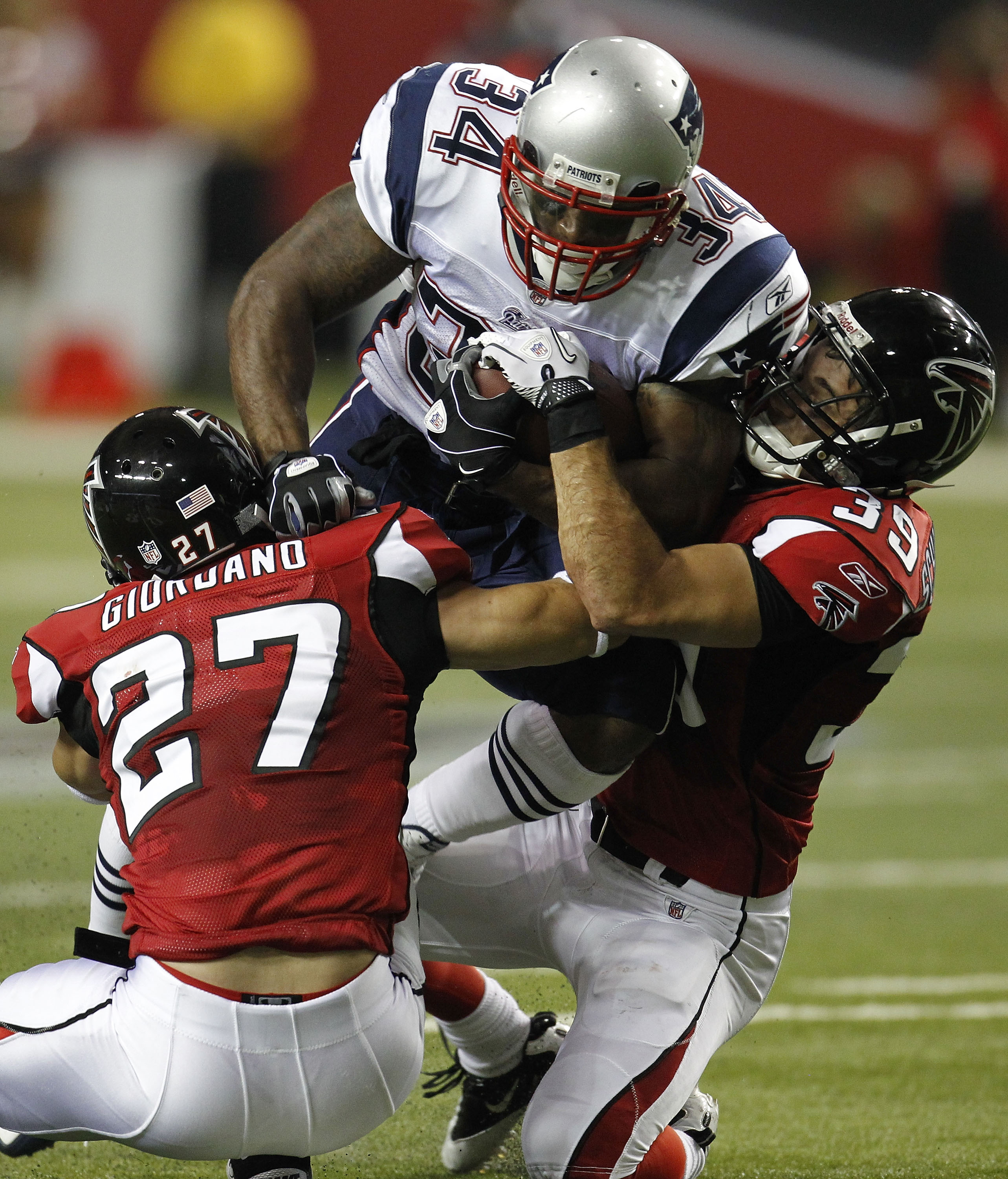 ATLANTA - AUGUST 19:  Running back Sammy Morris #34 of the New England Patriots is tackled by safety Matt Giordano #27 and safety Shann Schillinger #39 of the Atlanta Falcons during the preseason game against the at the Georgia Dome on August 19, 2010 in
