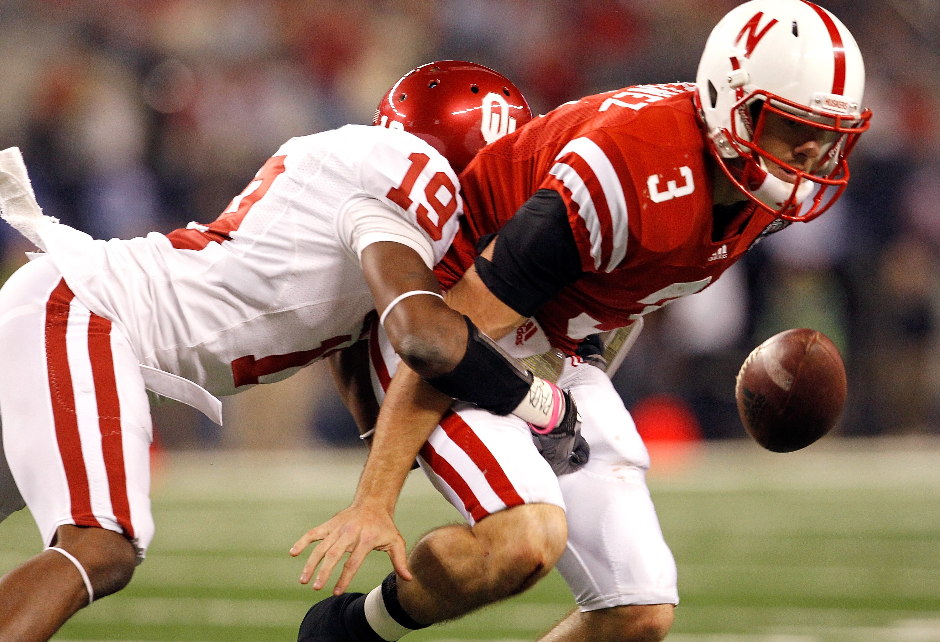 ARLINGTON, TX - DECEMBER 04:  Quarterback Taylor Martinez #3 of the Nebraska Cornhuskers fumbles the ball under pressure from defensive back Demontre Hurst #19 of the Oklahoma Sooners at Cowboys Stadium on December 4, 2010 in Arlington, Texas. The Sooners
