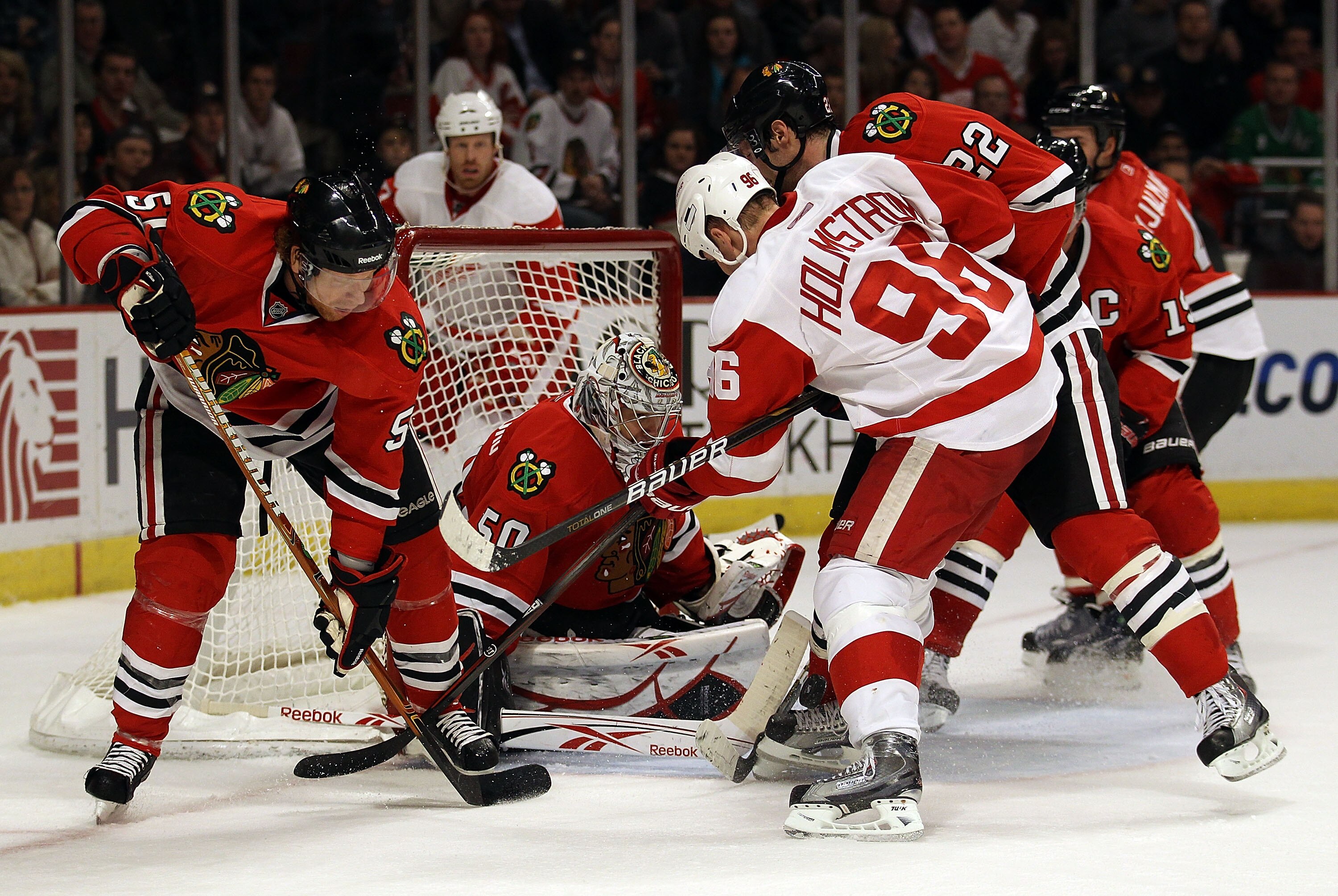 CHICAGO, IL - DECEMBER 17: Corey Crawford #50 of the Chicago Blackhawks makes a save against Tomas Holmstrom #96 of the Detroit Red Wings as teammates (L-R) Brian Campbell #51, John Scott #32 and Jonathan Toews #19 defend at the United Center on December 