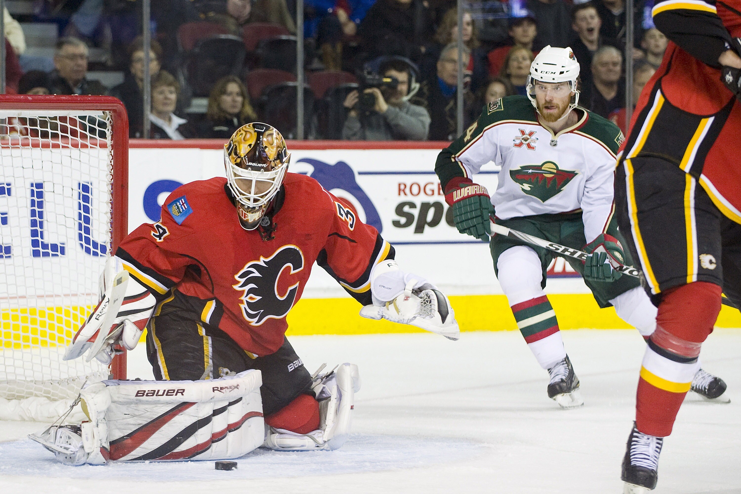 EDMONTON, AB - NOVEMBER 29:  Miikka Kiprusoff #34 of the Calgary Flames makes a pad save as Martin Havlat #24 of the Minnesota Wild looks on at Scotiabank Saddledome on November 29, 2010 in Calgary, Alberta, Canada. The Flames beat the Wild 3-0.  (Photo b