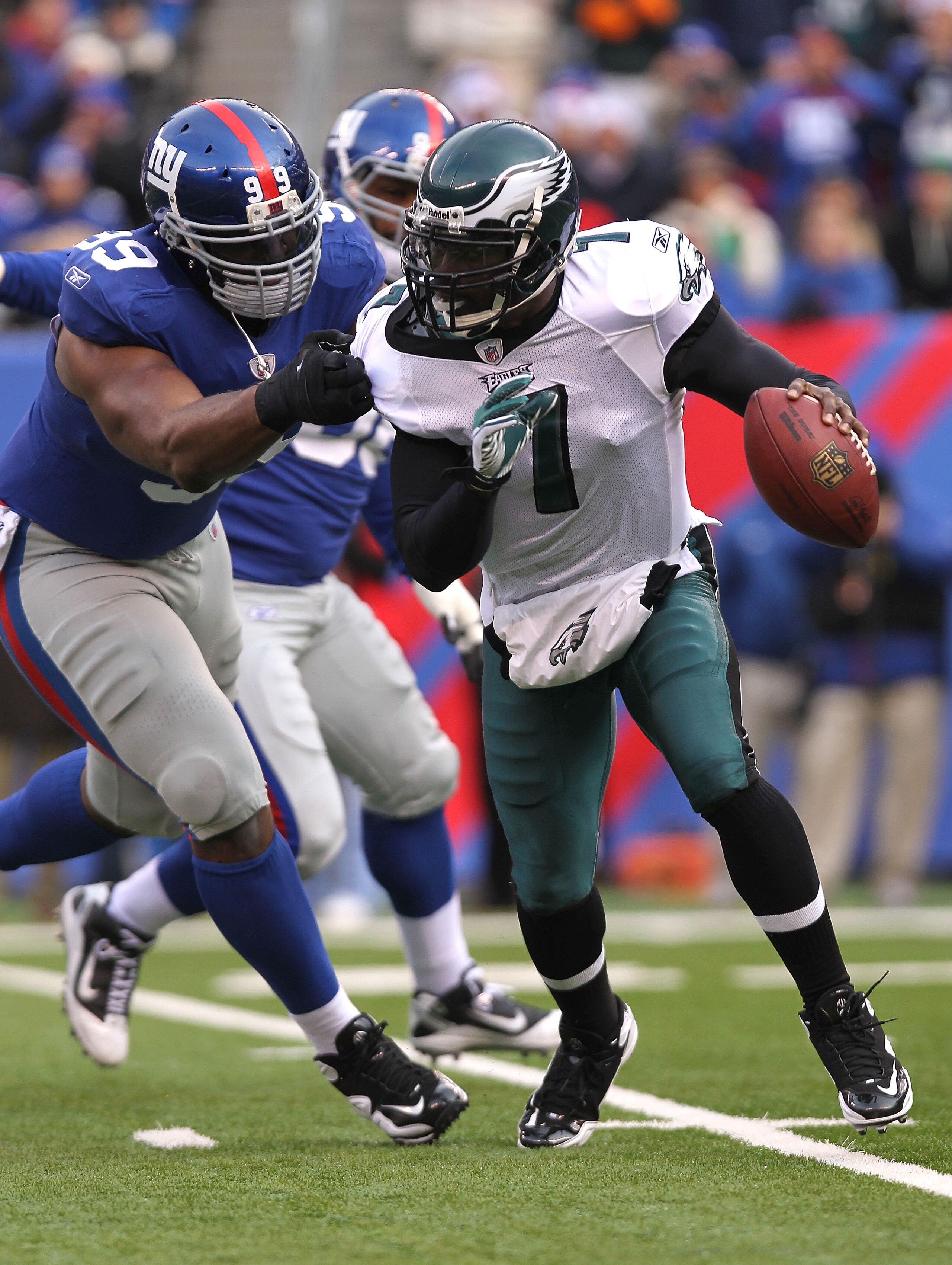 EAST RUTHERFORD, NJ - DECEMBER 19:  Michael Vick #7 of the Philadelphia Eagles runs from the tackle of Chris Canty #99 of the New York Giants at New Meadowlands Stadium on December 19, 2010 in East Rutherford, New Jersey.  (Photo by Nick Laham/Getty Image