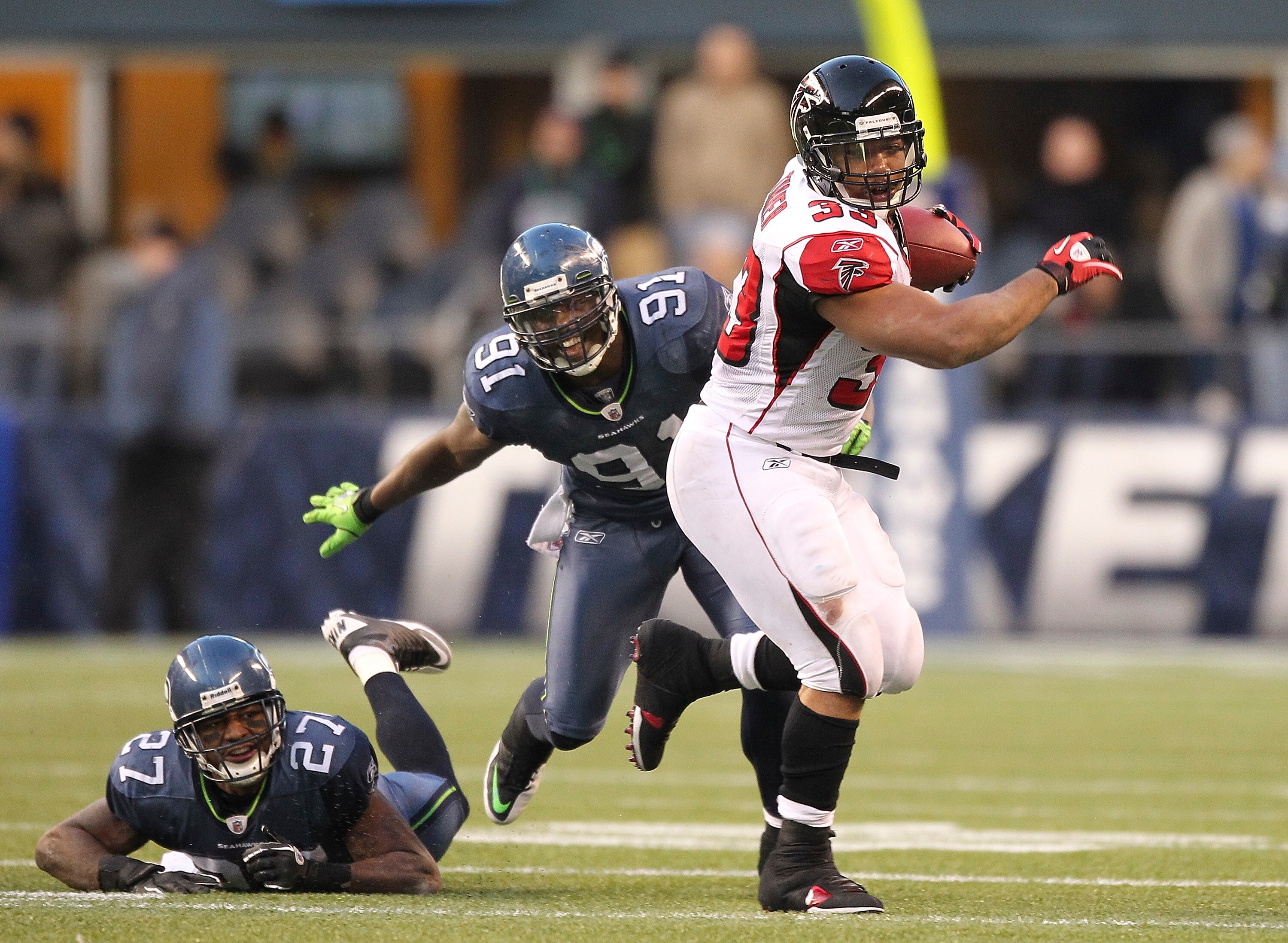 SEATTLE, WA - DECEMBER 19:  Running back Michael Turner #33 of the Atlanta Falcons rushes against Chris Clemons #91 and Jordan Babineaux #27 of the Seattle Seahawks at Qwest Field on December 19, 2010 in Seattle, Washington. The Falcons defeated the Seaha