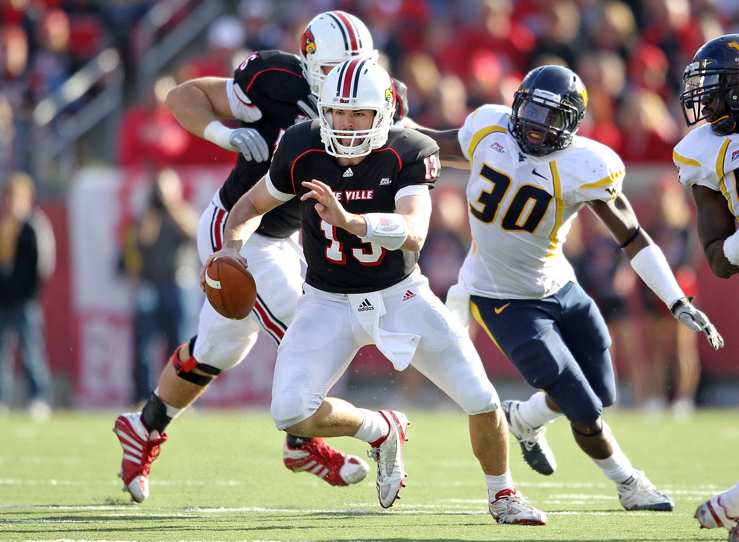 LOUISVILLE, KY - NOVEMBER 20: Justin Burke #13 of the Louisville Cardinals runs with the ball during the Big East Conference game against the West Virginia Mountaineers at Papa John's Cardinal Stadium on November 20, 2010 in Louisville, Kentucky.  (Photo