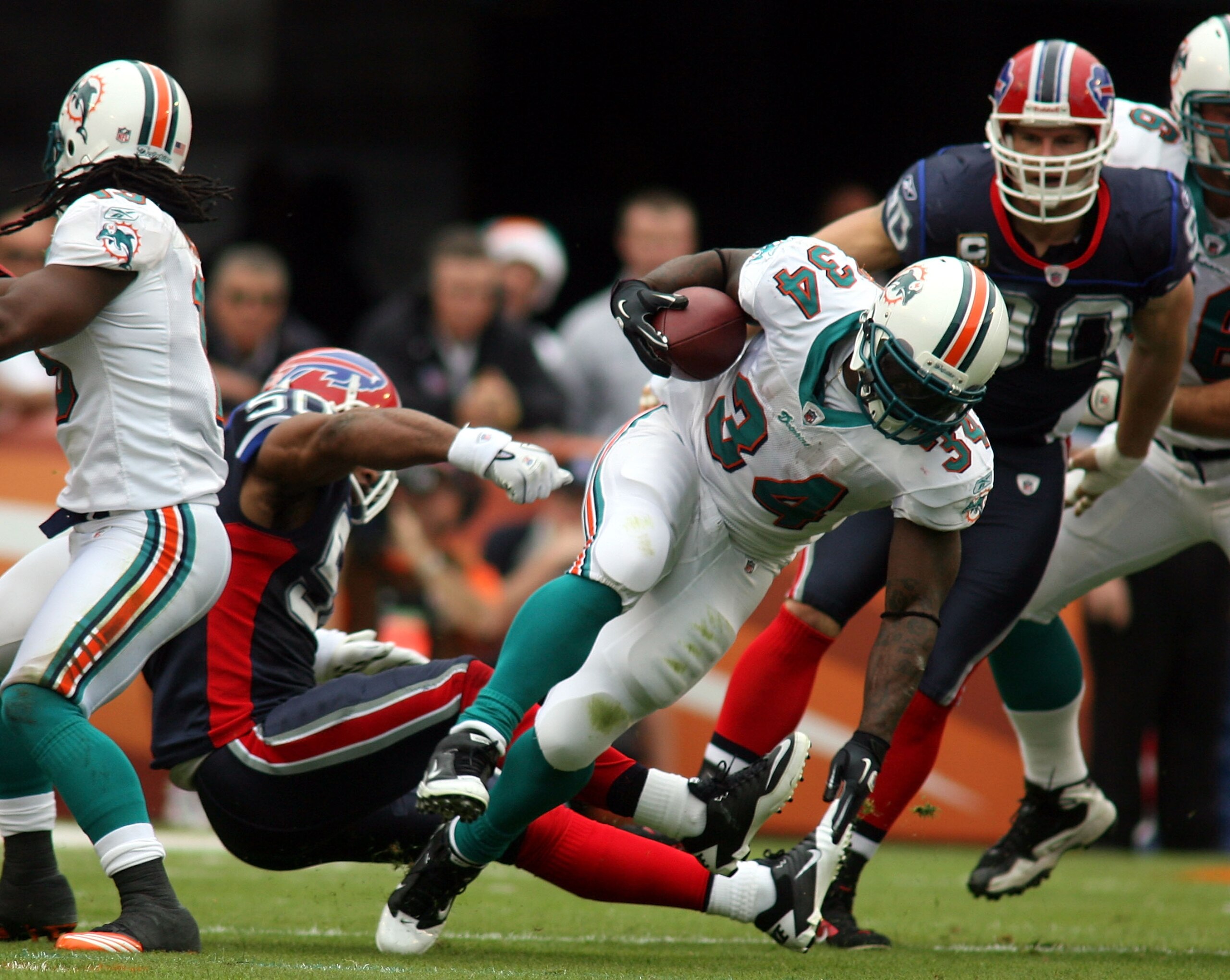 MIAMI, FL - DECEMBER 19:  Running back Ricky Williams #34 of the Miami Dolphins is upended by cornerback Donte Whitner #20 of the Buffalo Bills during a game at Sun Life Stadium on December 19, 2010 in Miami, Florida. The Bills defeated the Dolphins 17-14
