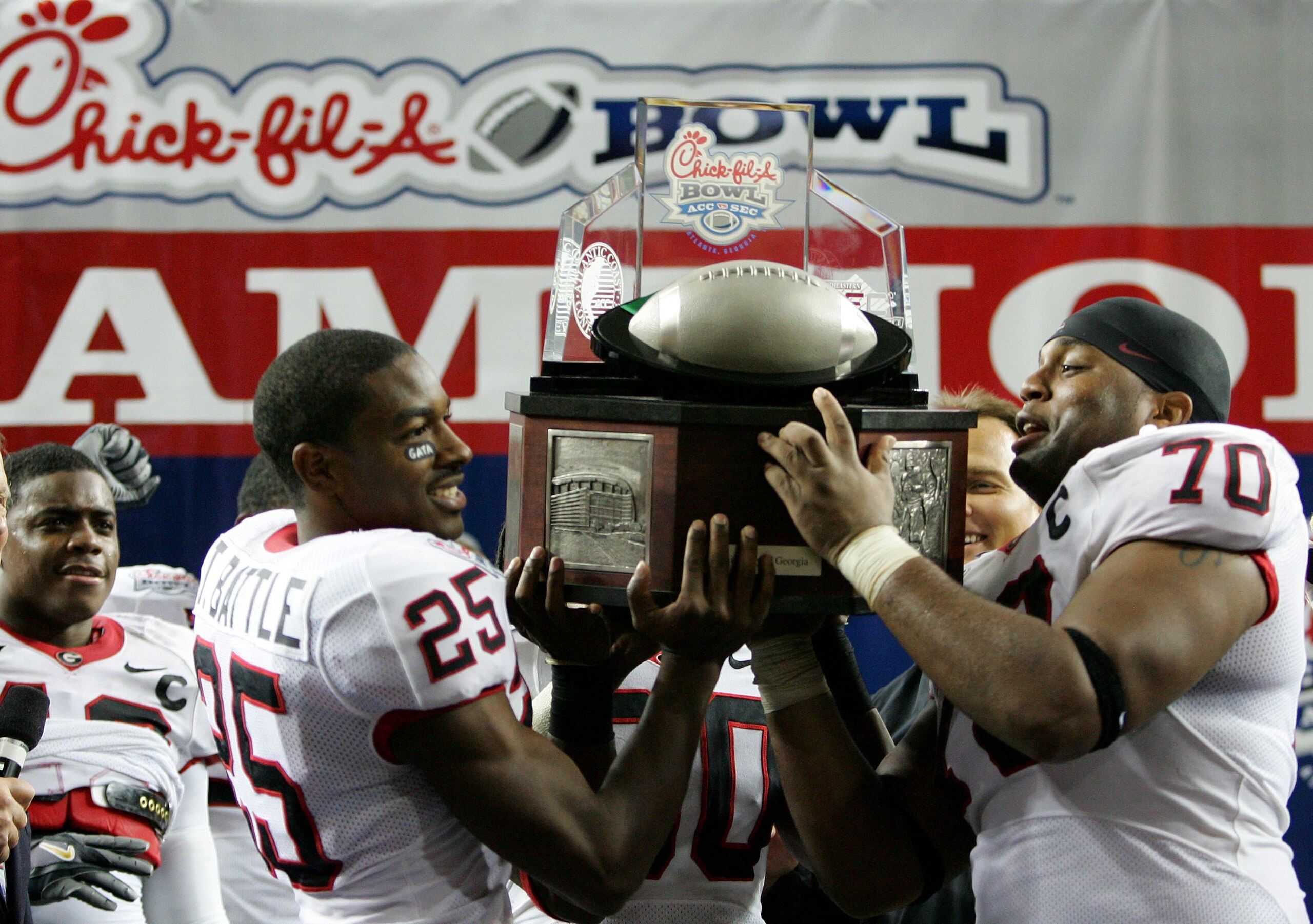 ATLANTA - DECEMBER 30:  Teammates Tra Battle #25 and Nick Jones #70 of the Georgia Bulldogs hold up the winner's trophy after defeating the Virginia Tech Hokies 31-24 in the Chick-fil-a Bowl on December 30, 2006 at the Georgia Dome in Atlanta, Georgia.  (