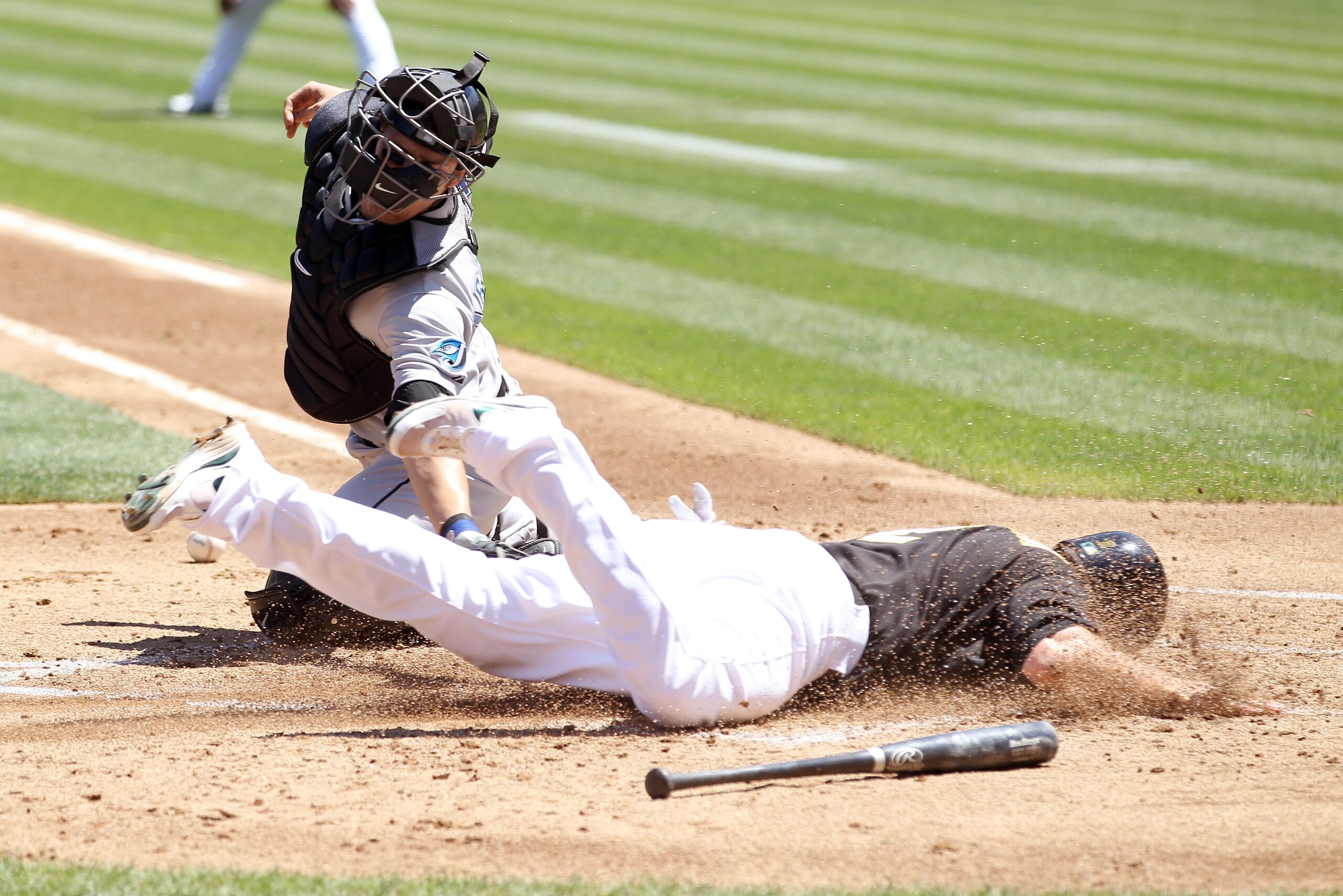 OAKLAND, CA - AUGUST 18:  Cliff Pennington #2 of the Oakland Athletics safely slides past J.P. Arencibia #9 of the Toronto Blue Jays to give the Athletics a 3-0 lead over the Blue Jays in the third inning at the Oakland-Alameda County Coliseum on August 1