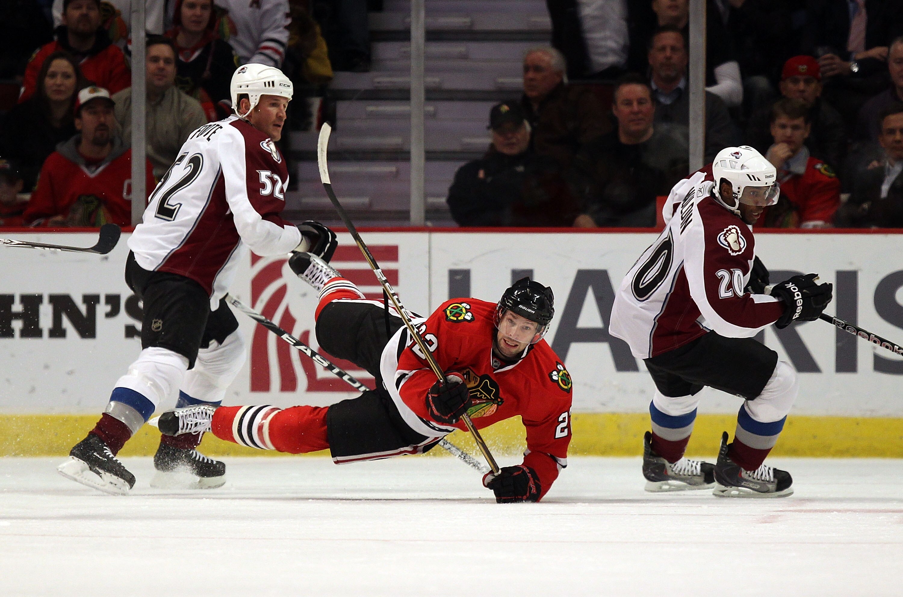 CHICAGO, IL - DECEMBER 15: Troy Brouwer #22 of the Chicago Blackhawks falls to the ice between Adam Foote #52 and Greg Mauldin #20 of the Colorado Avalanche at the United Center on December 15, 2010 in Chicago, Illinois. (Photo by Jonathan Daniel/Getty Im