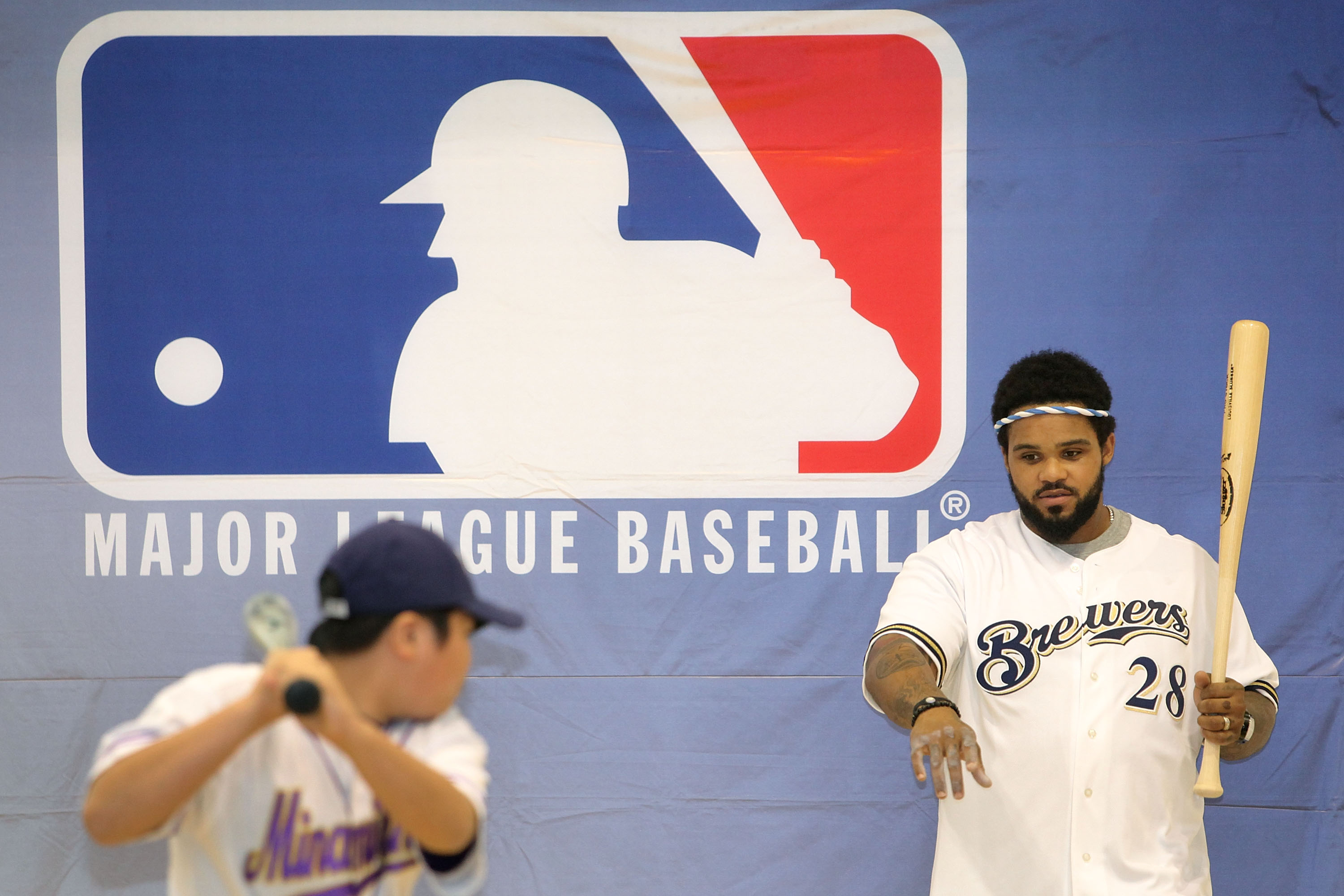 TOKYO - DECEMBER 15:  Prince Fielder of the Milwaukee Brewers coaches a member of the baseball club in batting skills while visiting Minamisuna Junior High School as part of the Major League Baseball (MLB) International Ambassador program to promote the g