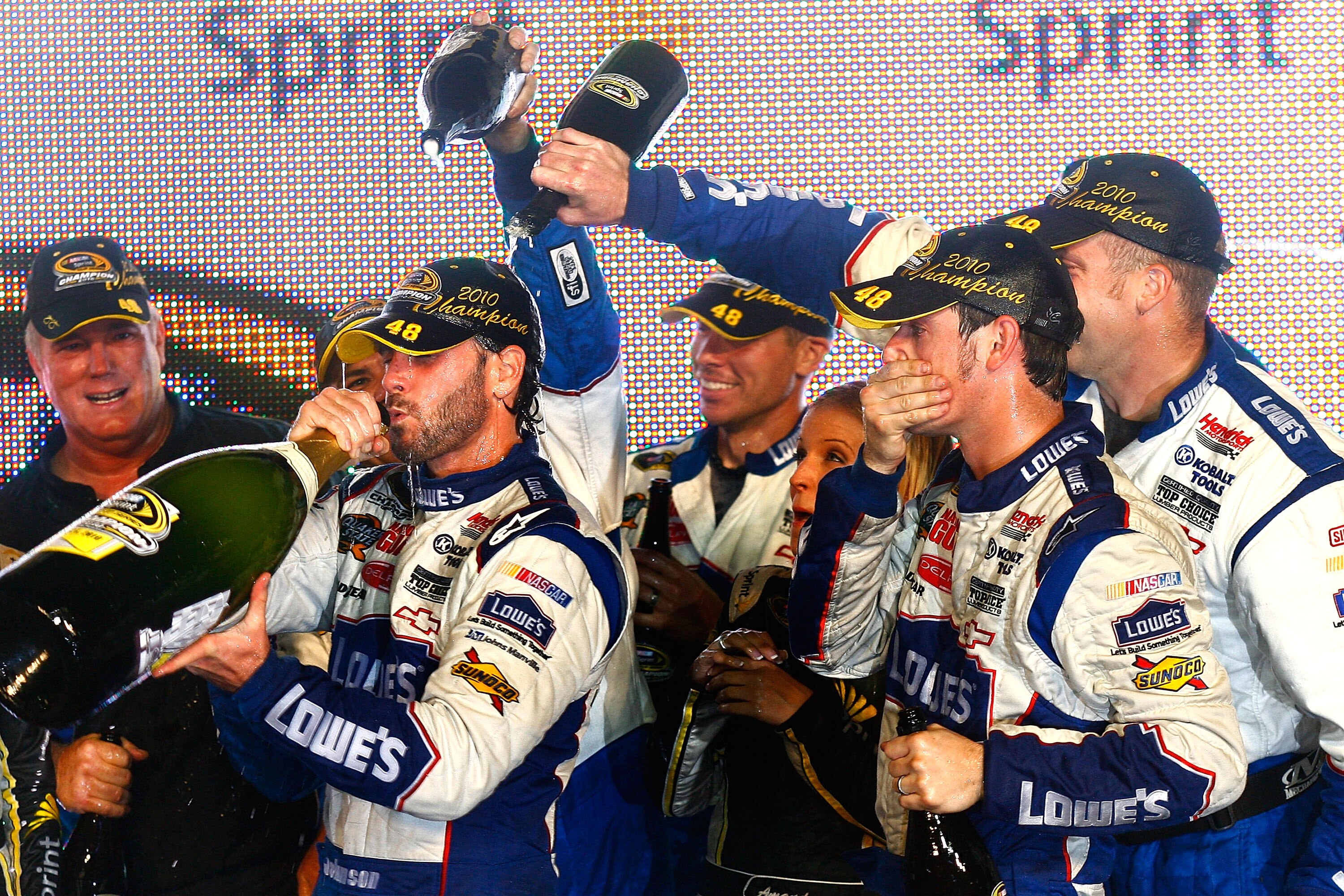 HOMESTEAD, FL - NOVEMBER 21:  Jimmie Johnson (L), driver of the #48 Lowe's Chevrolet, drinks champagne in celebration with teammates after winning his fifth consecutive NASCAR Sprint Cup championship following the Ford 400 at Homestead-Miami Speedway on N